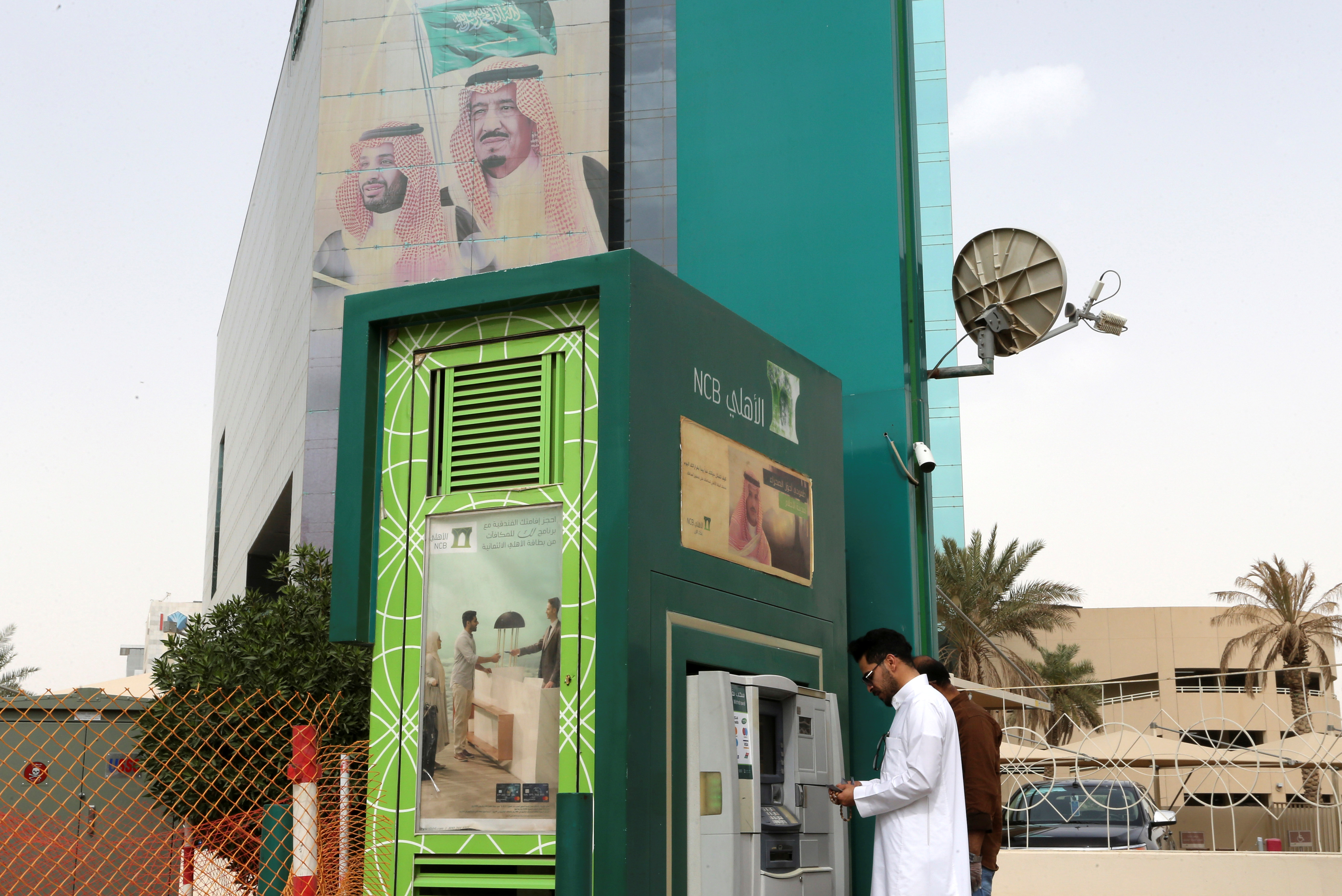A man withdraws money from an ATM outside the Saudi NCB bank, after an outbreak of coronavirus, in Riyadh