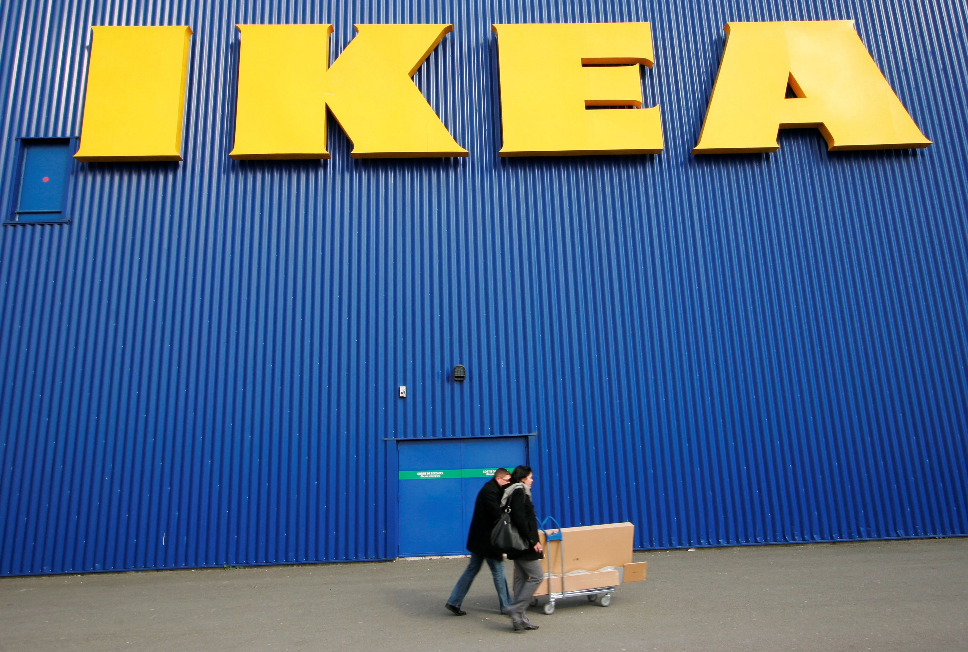 People push a shopping cart past a warehouse of the Swedish furniture maker IKEA in Bordeaux