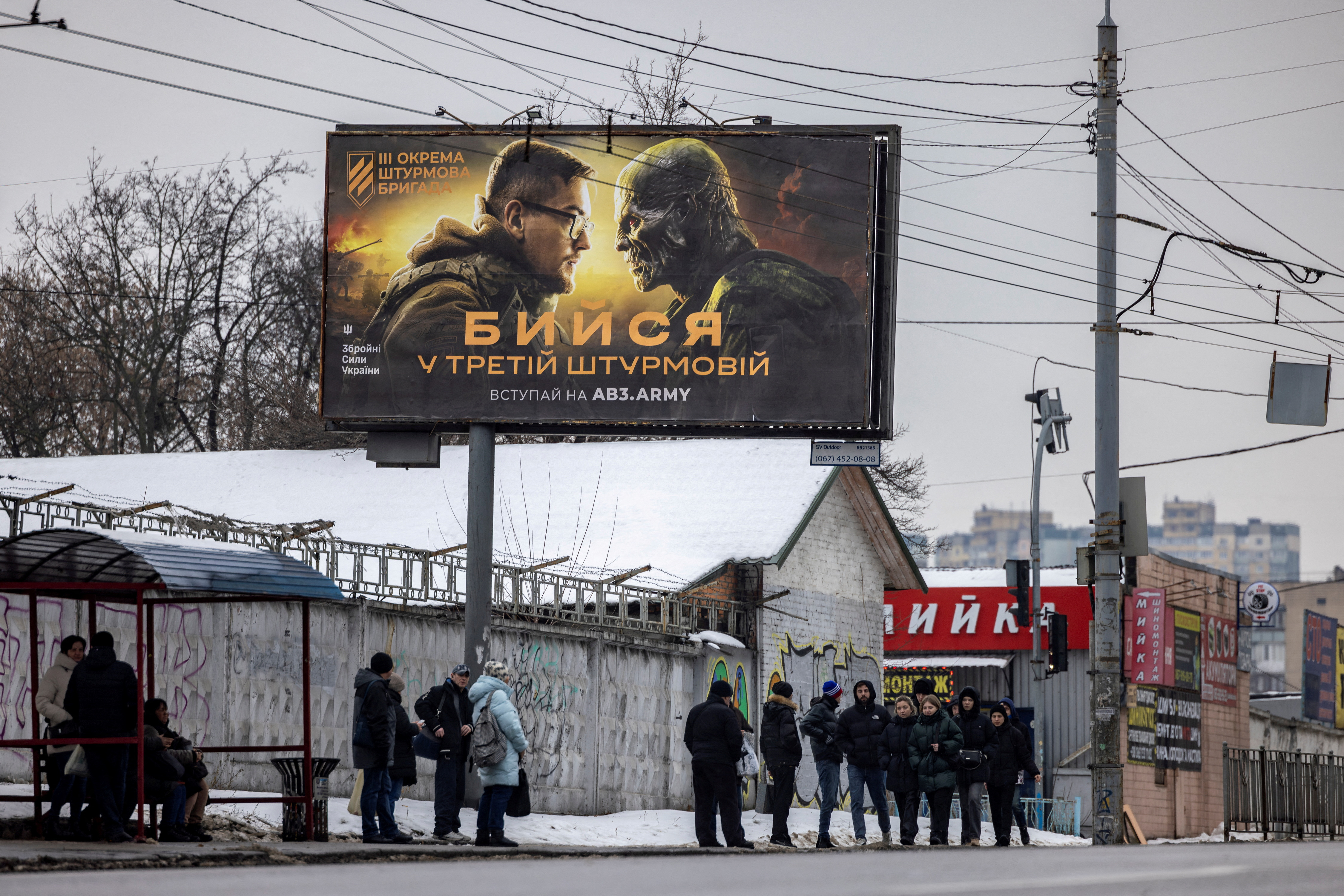 People walk past a poster advertising the 3rd Separate Assault Brigade of the Ukrainian Ground Forces in Kyiv