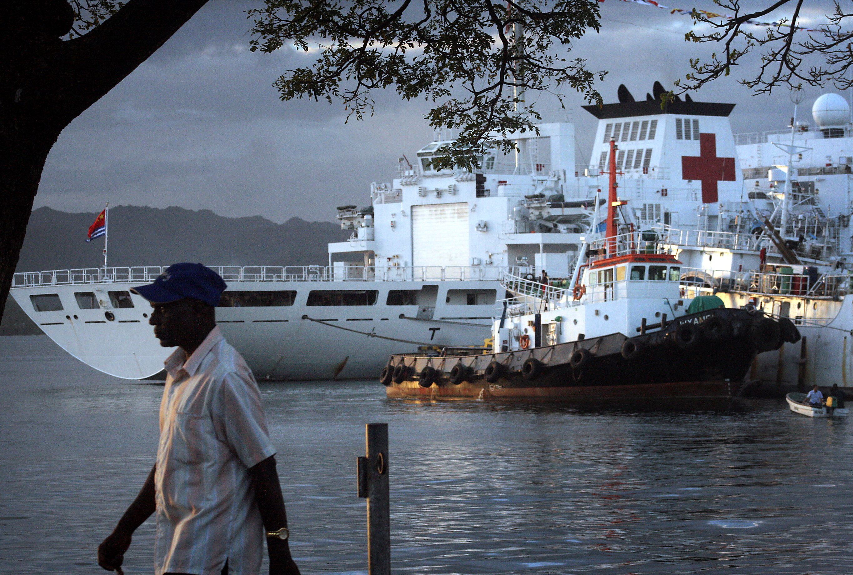A Man walks past a Chinese hospital ship called The Peace Ark, which offers free health care as it sails through the South Pacific, as it sits moored in the harbour of the Fiji capital of Suv