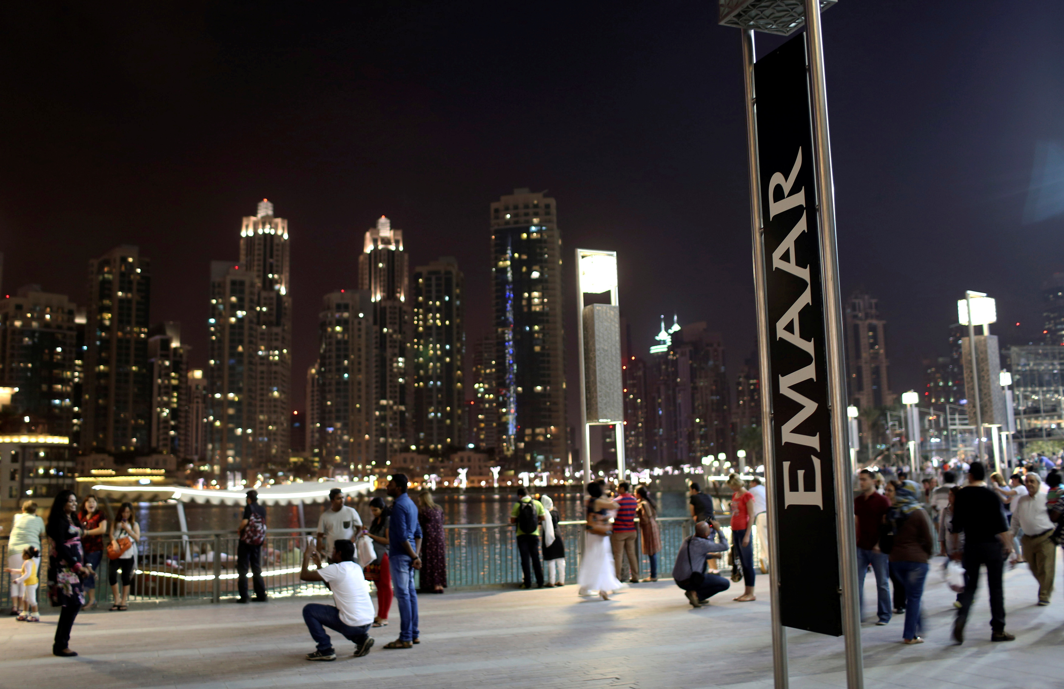 People have their pictures taken near an Emaar sign outside the Dubai Mall