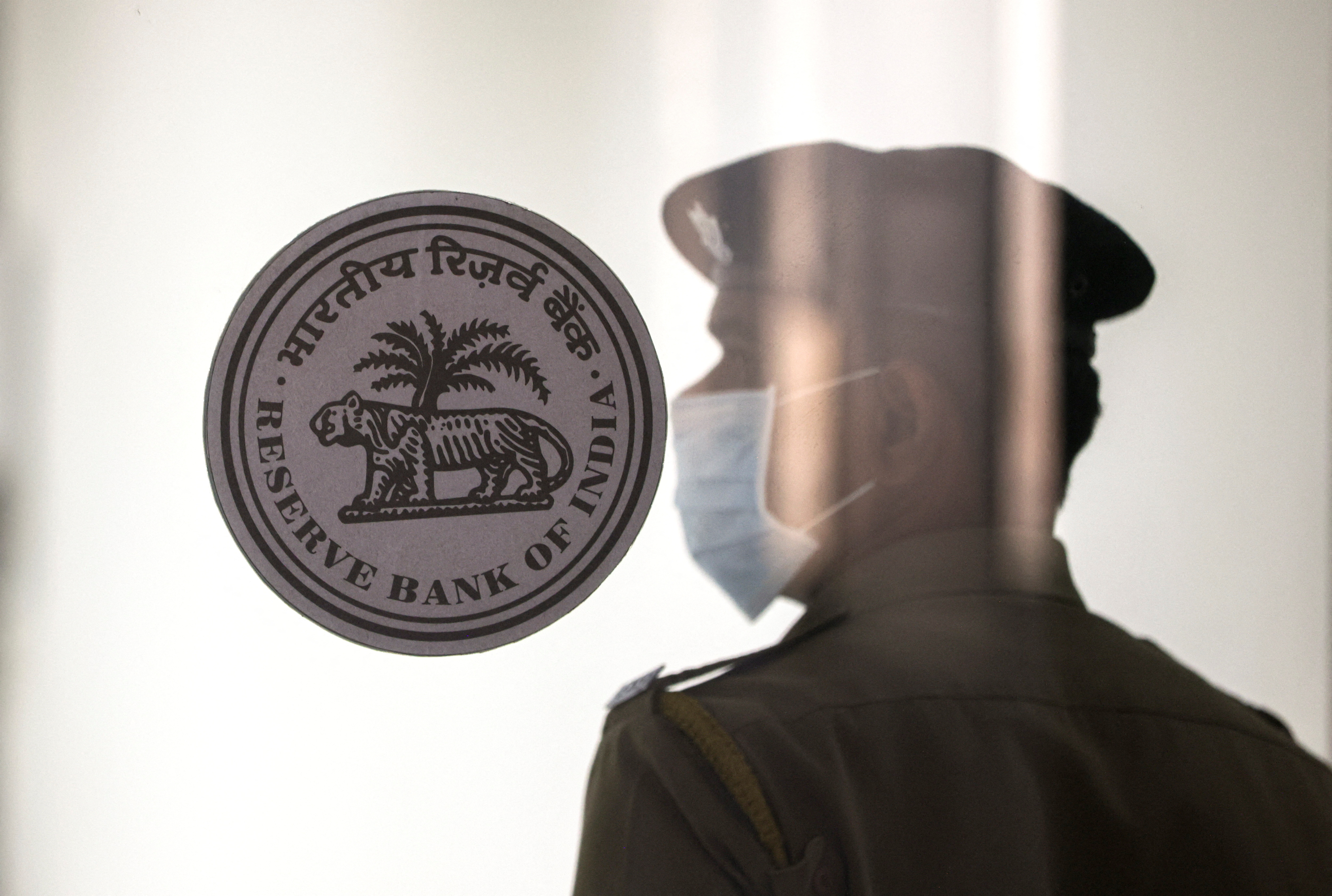 A security guard stands next to the logo of the Reserve Bank of India (RBI) inside its headquarters in Mumbai