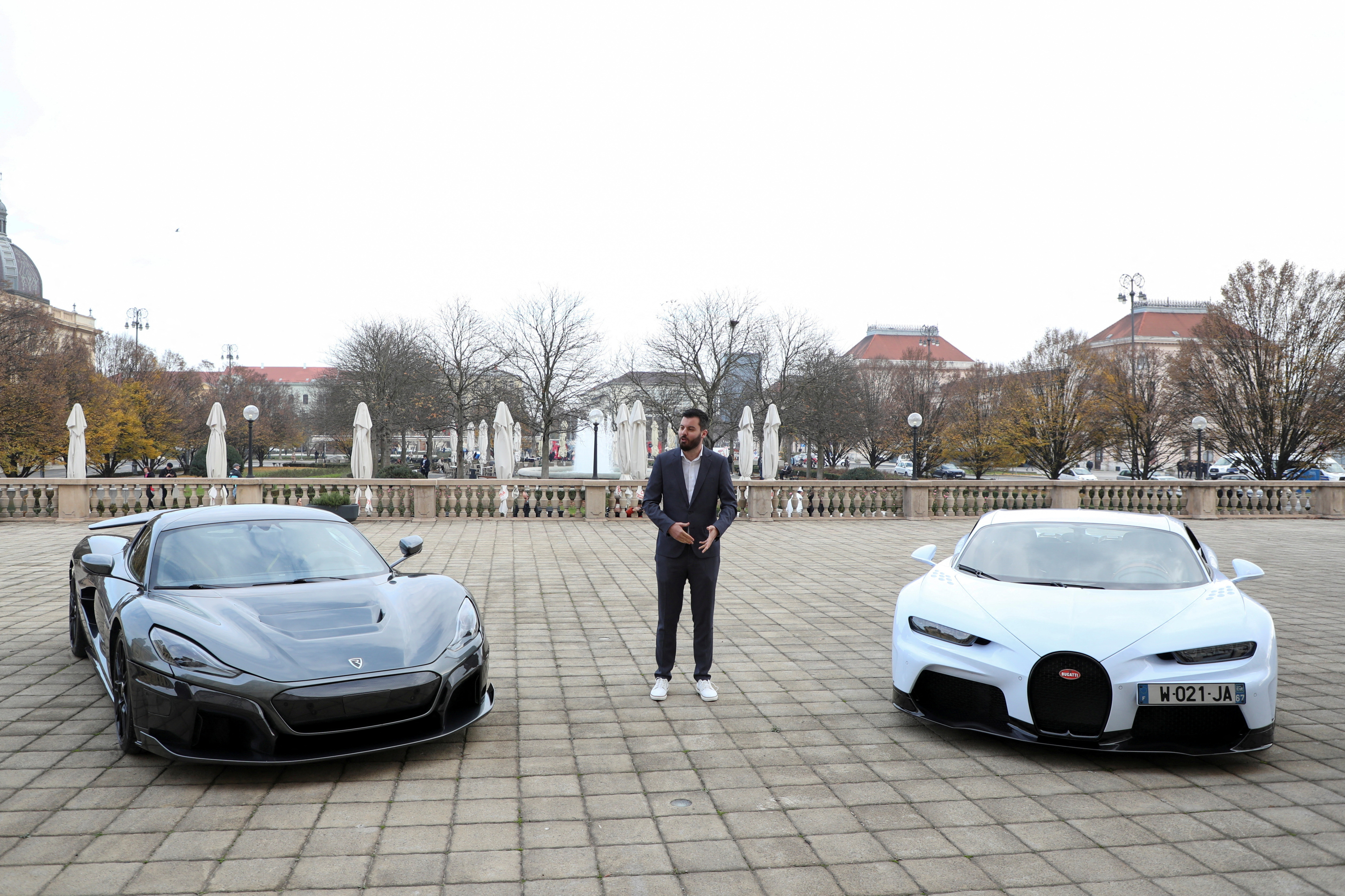 Rimac CEO stands next to a Rimac Nevera and Bugatti car