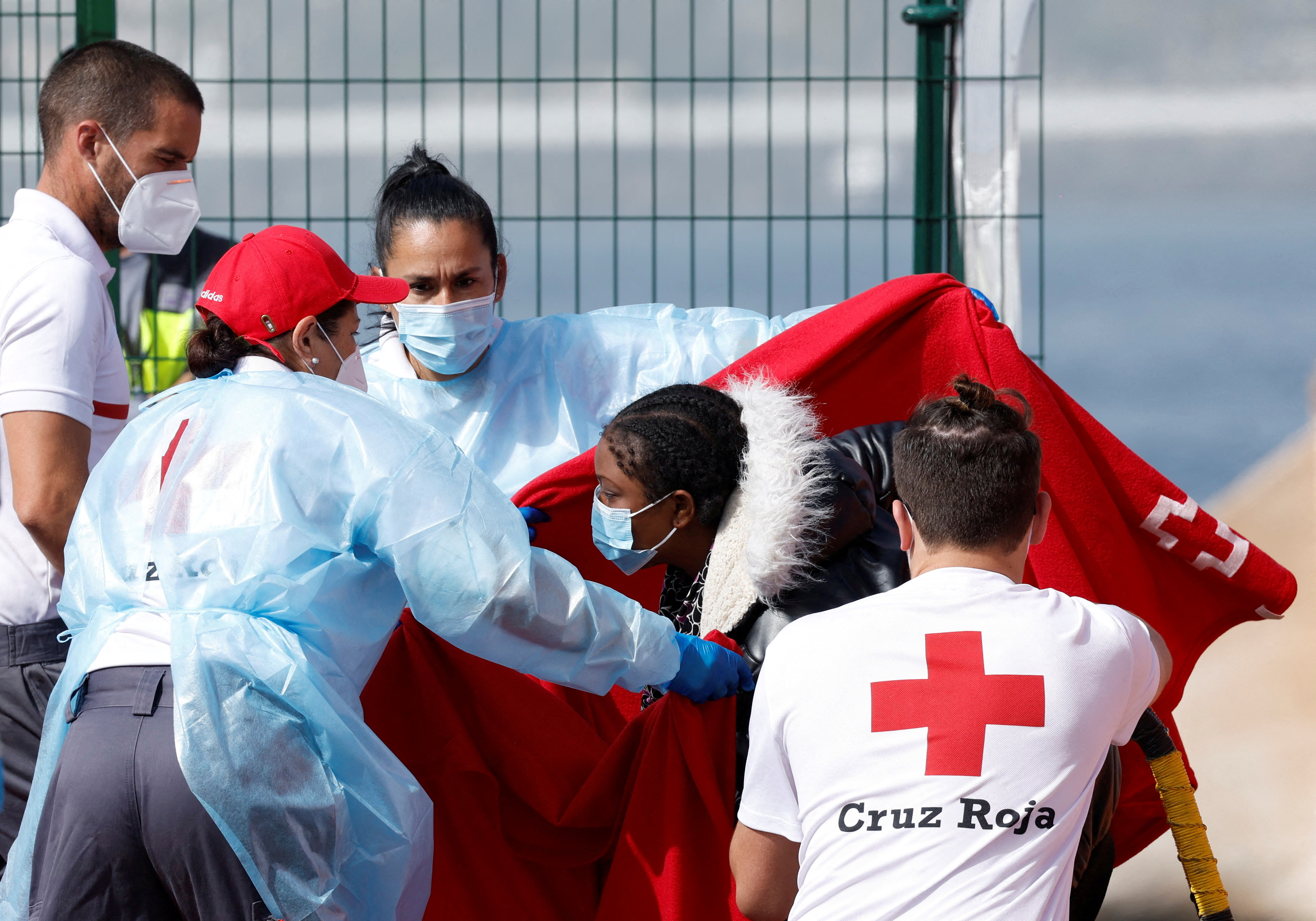 Rescuers help a migrant to disembark from a Spanish coast guard vessel in the port of Arguineguin