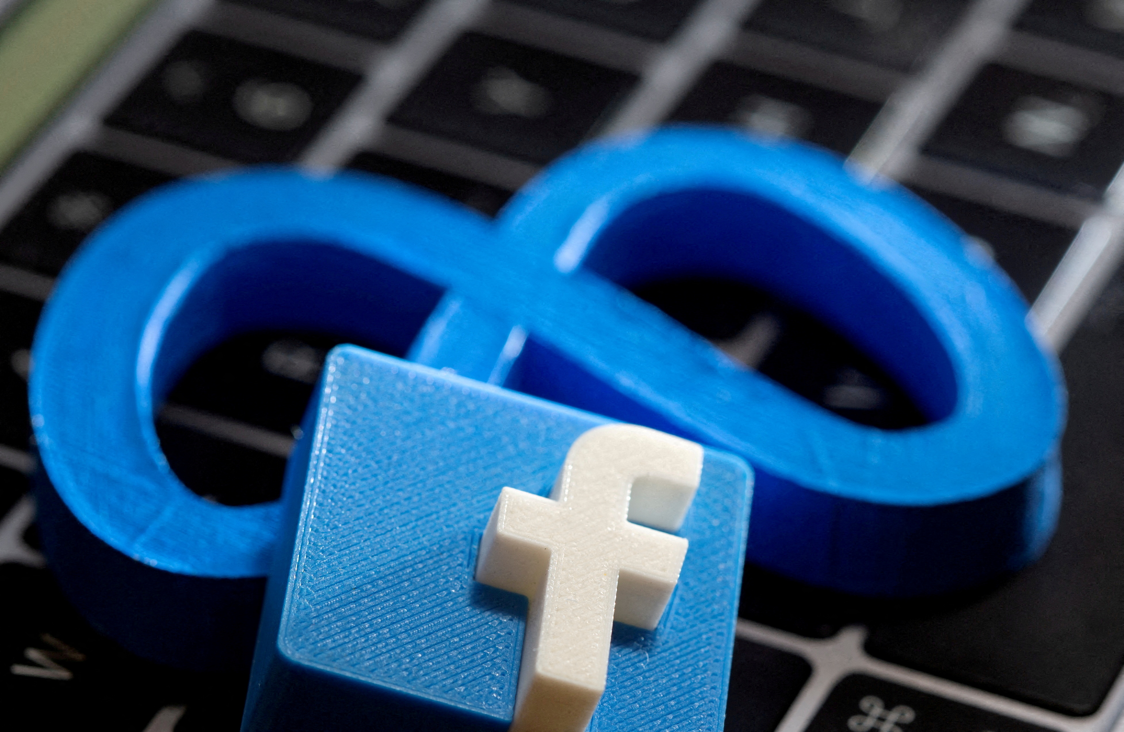 A 3D-printed logo of Facebook sits atop logo of Facebook parent Meta in this photo illustration
