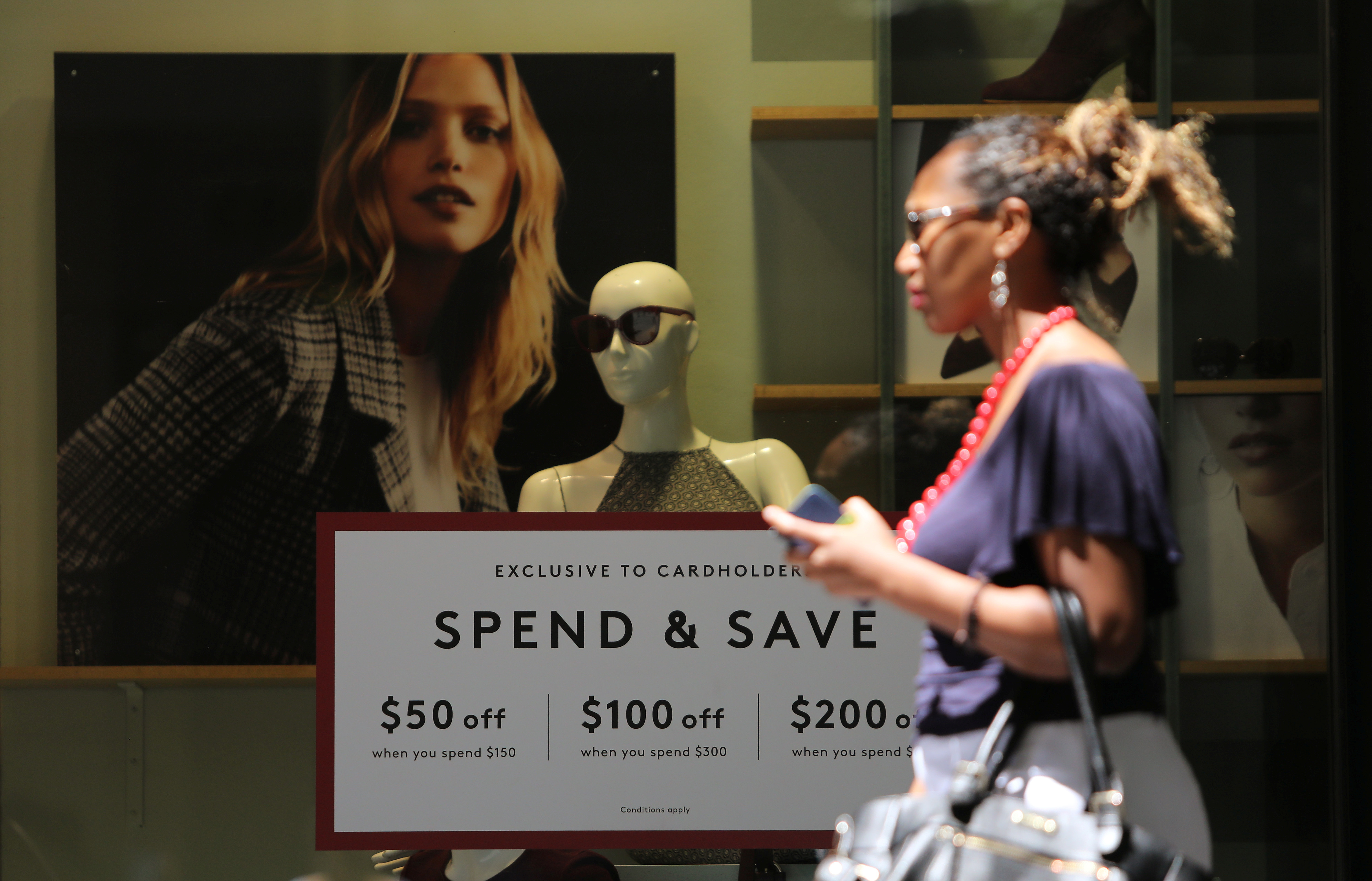 A woman walks past a display promoting discounts in Sydney