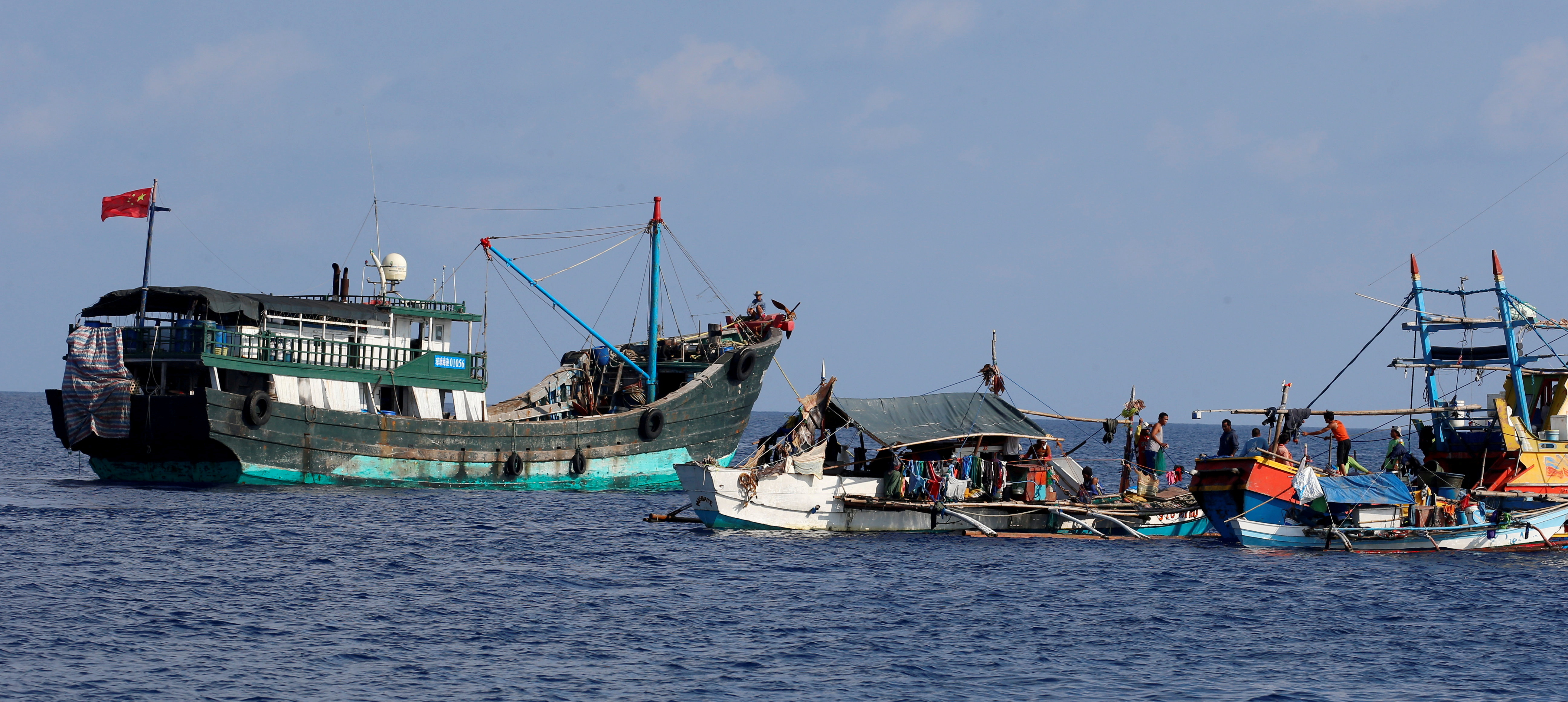A Chinese fishing vessel is anchored next to Filipino fishing boats at the disputed Scarborough Shoal