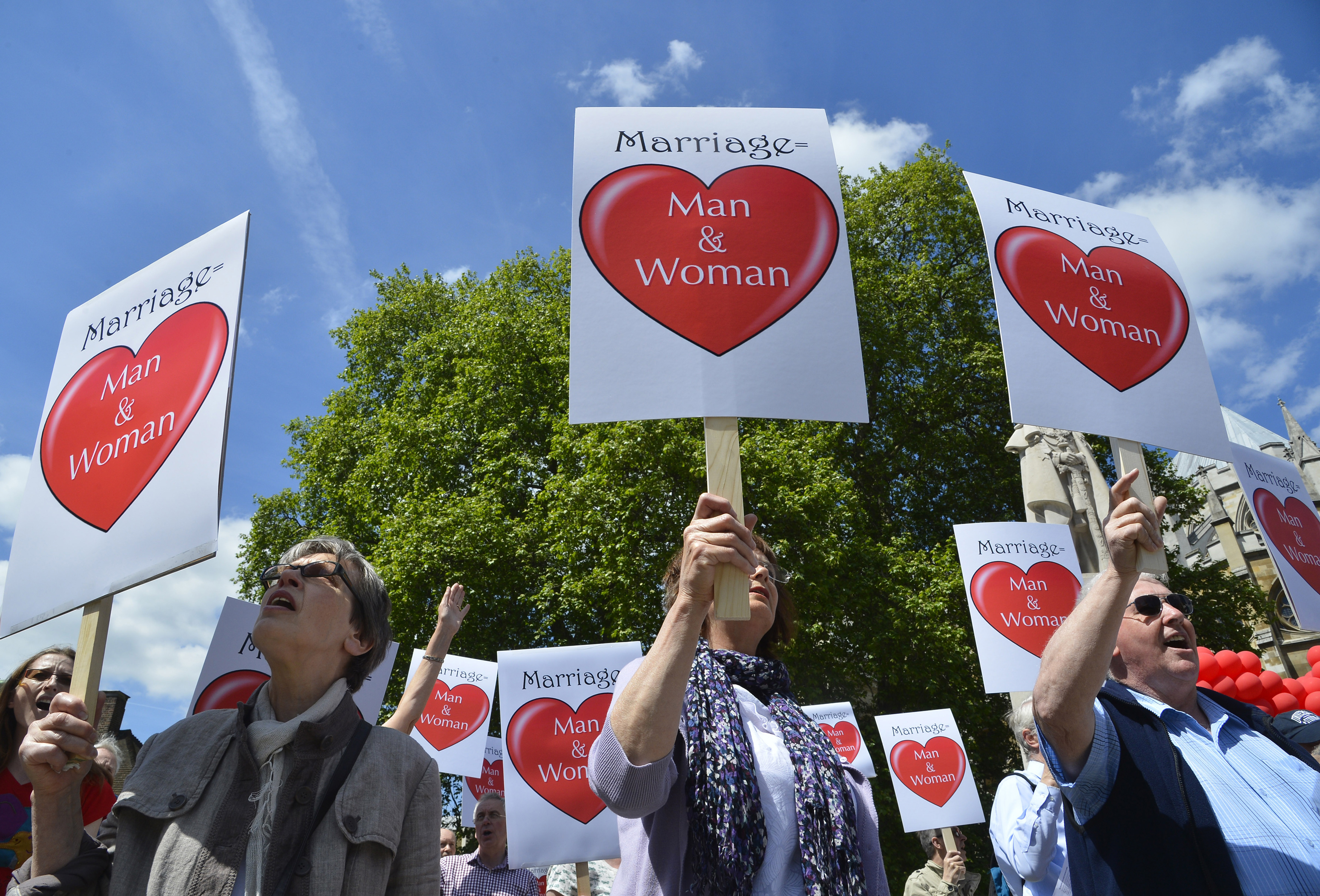 Protesters hold placards outside of the Houses of Parliament in London