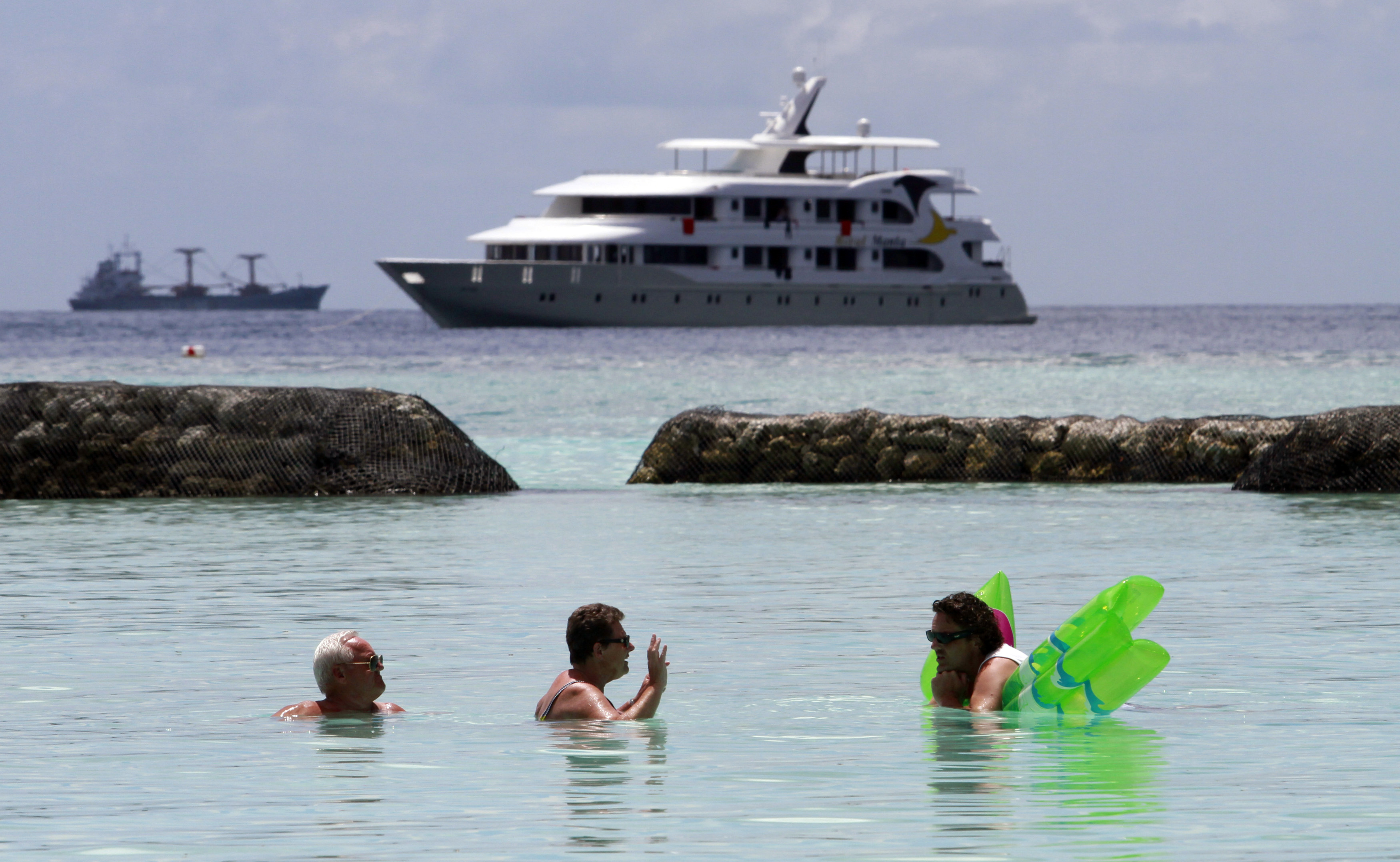 Tourists enjoy the sea as a safari boat sails past, near Vihamanafushi island