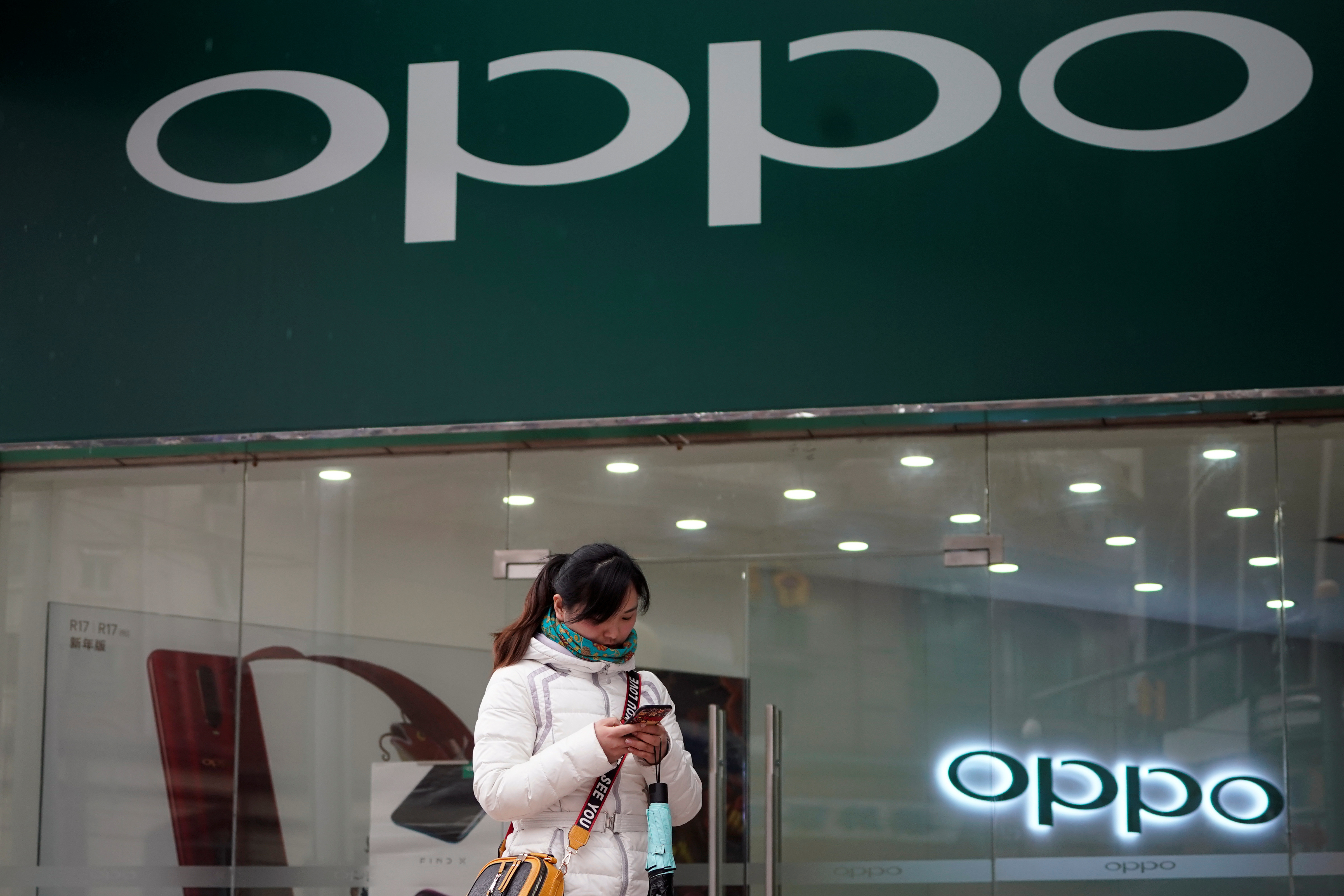 A woman walks by an Oppo logo at a shopping mall in Shanghai