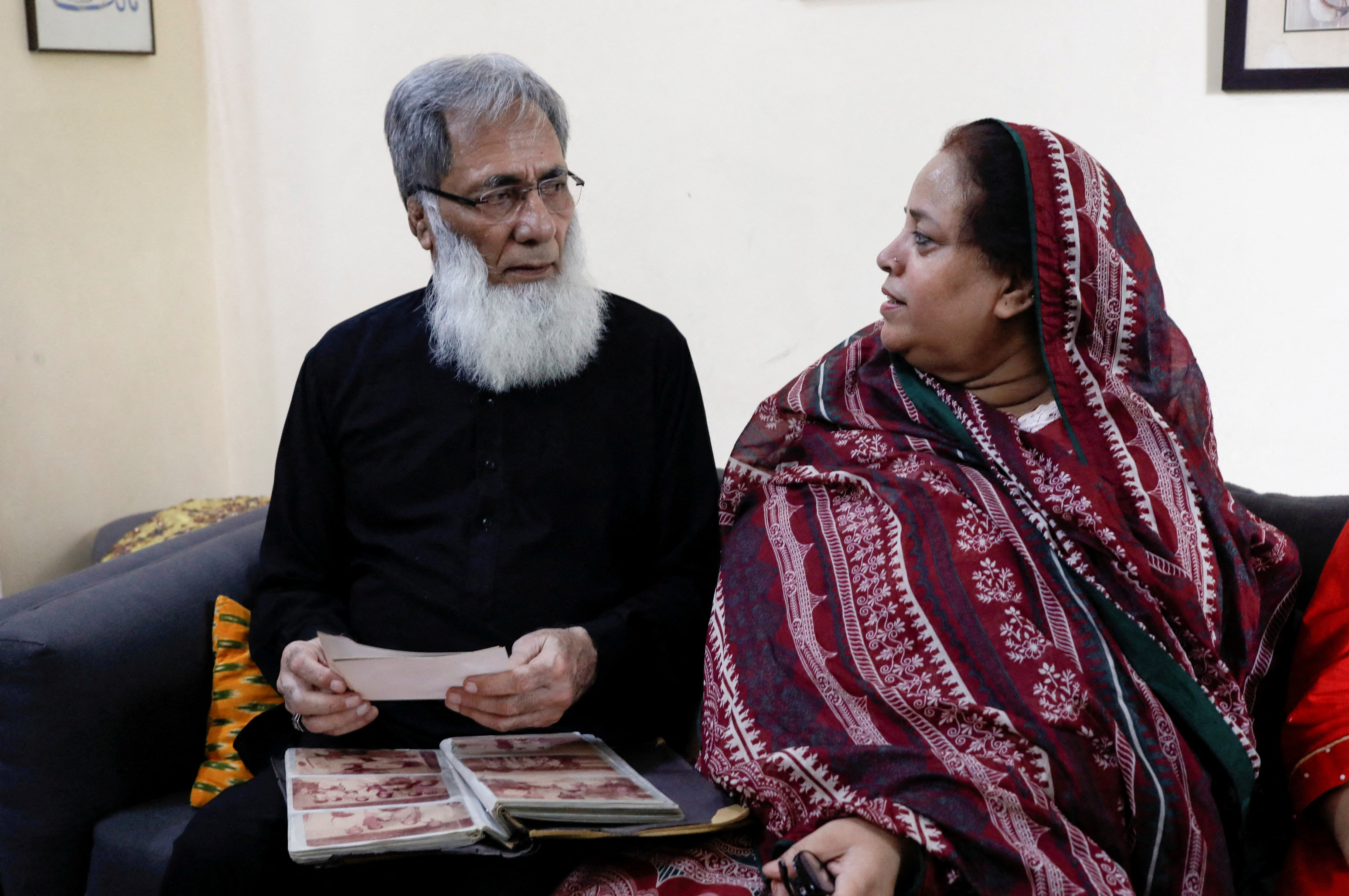Ali Hasan Baqai, whose family was divided by the partition of the subcontinent in 1947, speaks with his wife as they go through the family picture album, at home in Karachi,