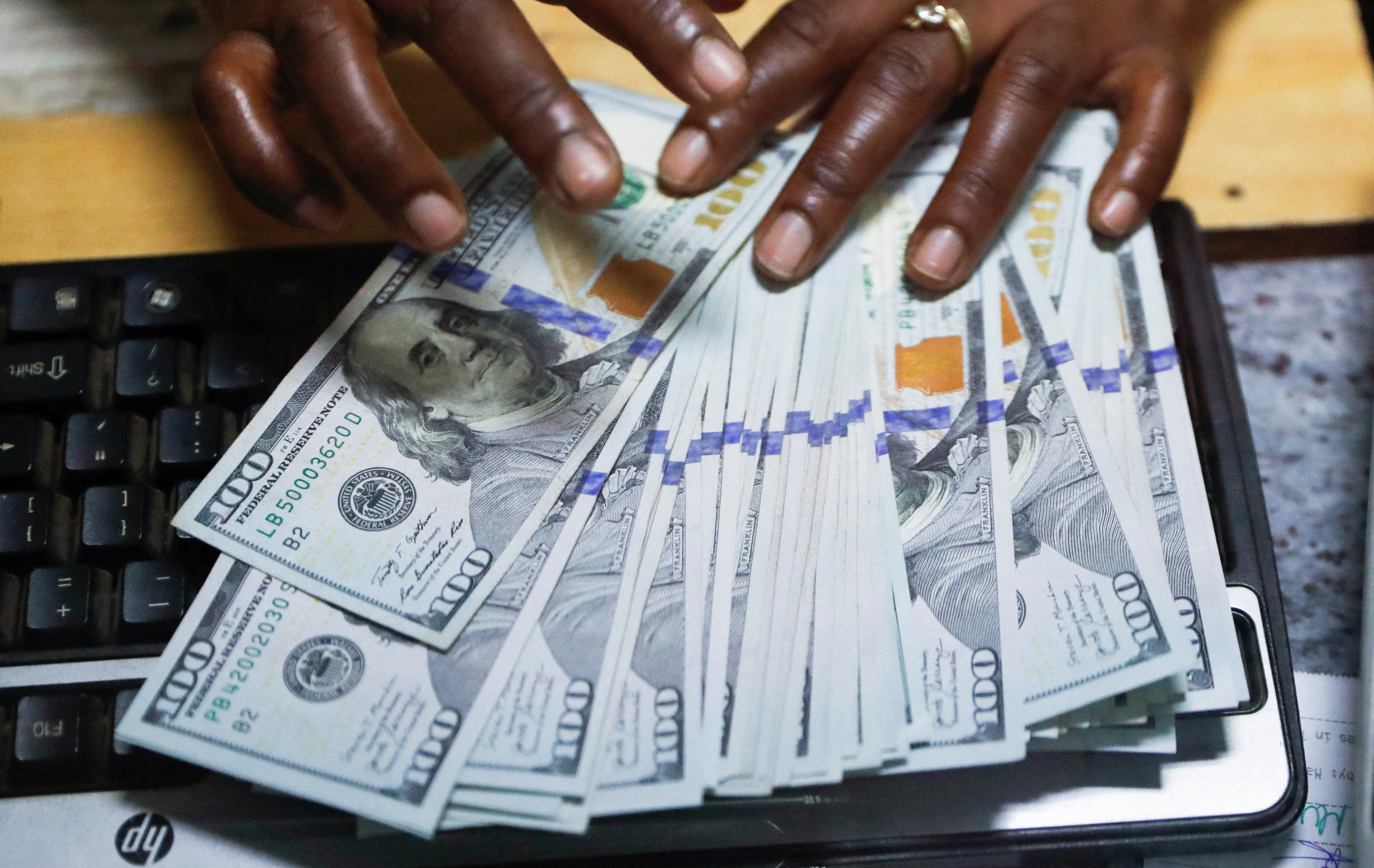 Teller sorts U.S. dollar banknotes inside the cashier's booth at a forex exchange bureau in downtown Nairobi