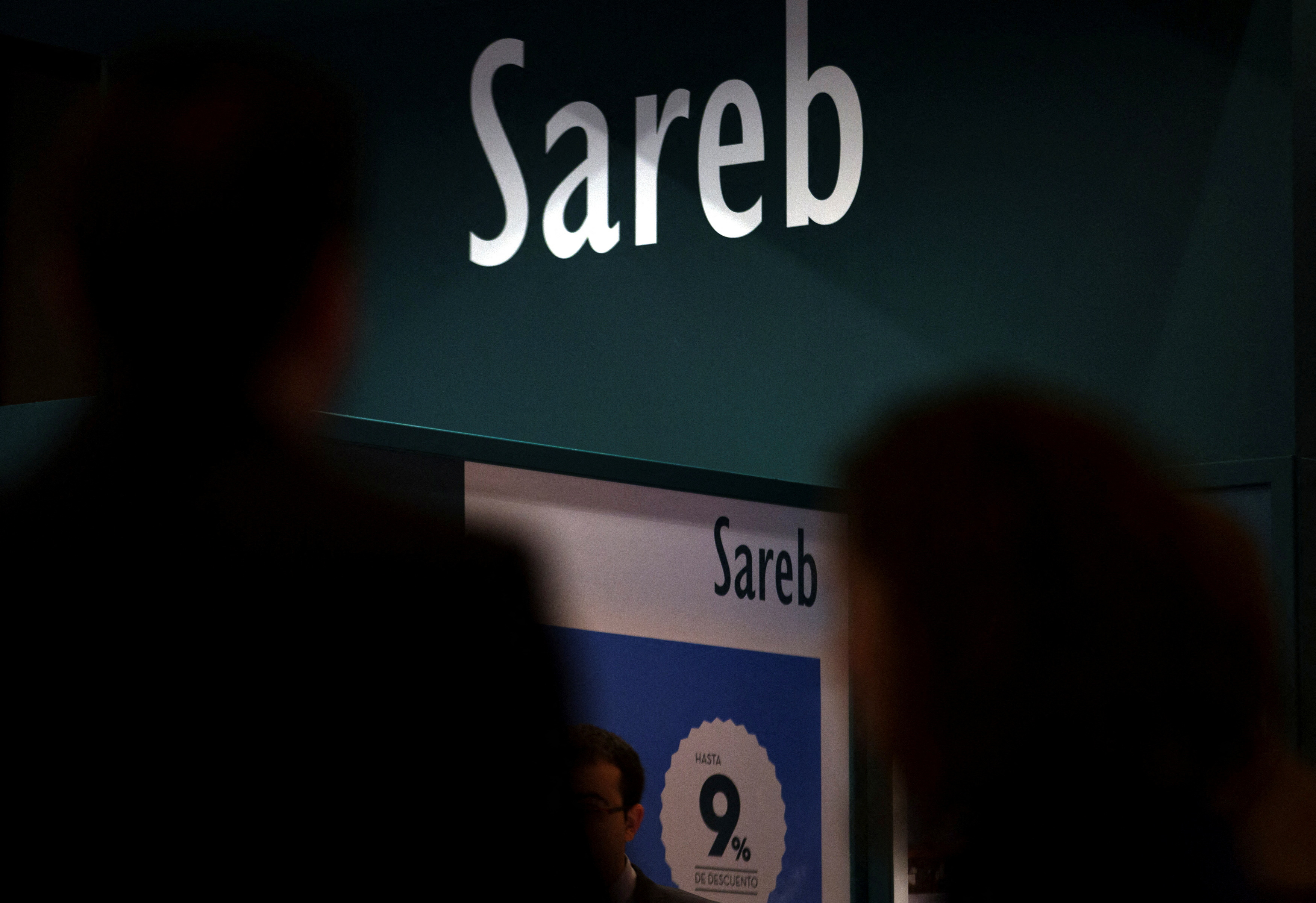 People walks past stand of Spain's bad bank Sareb during a real estate fair in Madrid