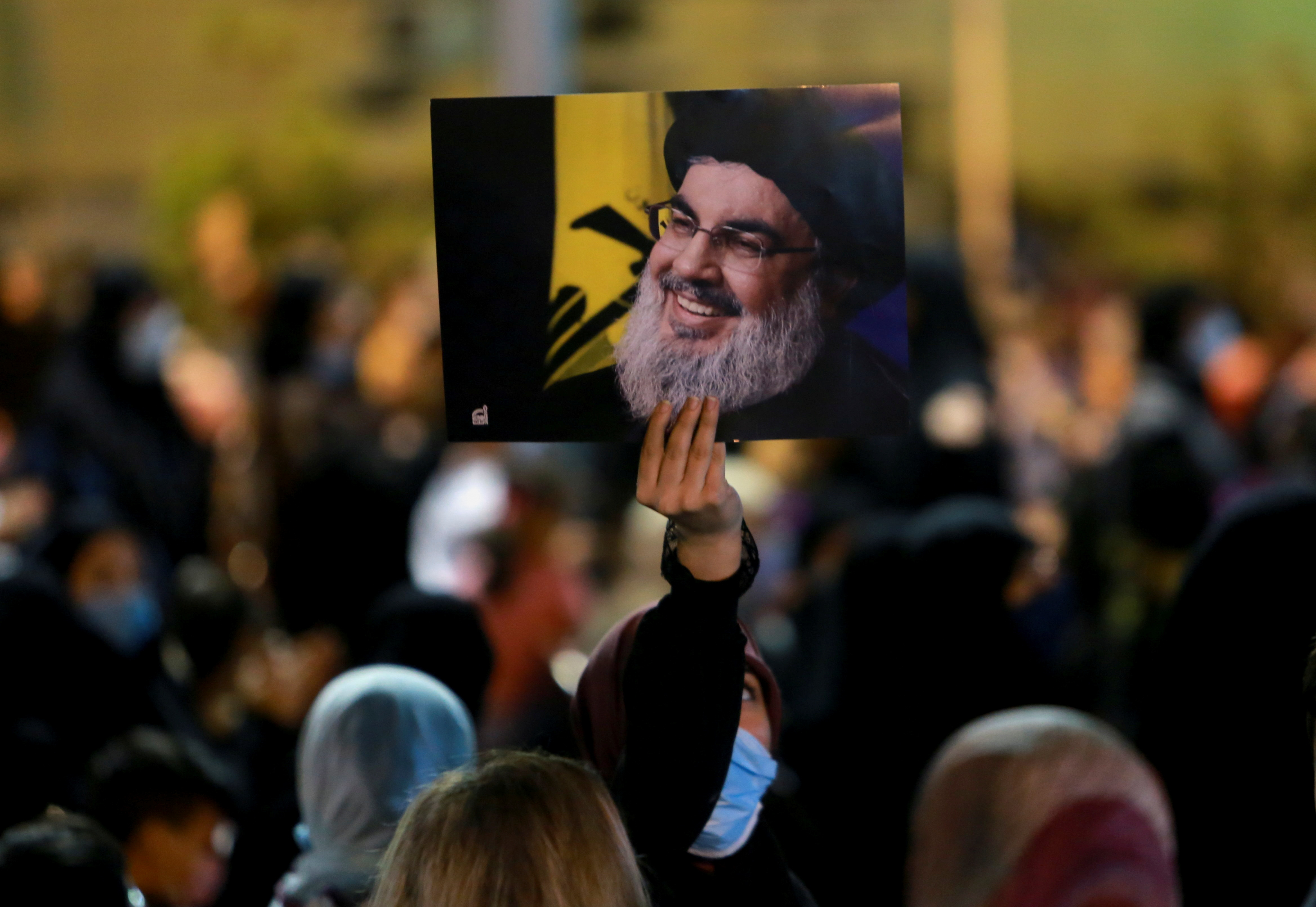 A supporter of Lebanon's Hezbollah leader Sayyed Hassan Nasrallah holds up his picture during a ceremony in Beirut's southern suburbs