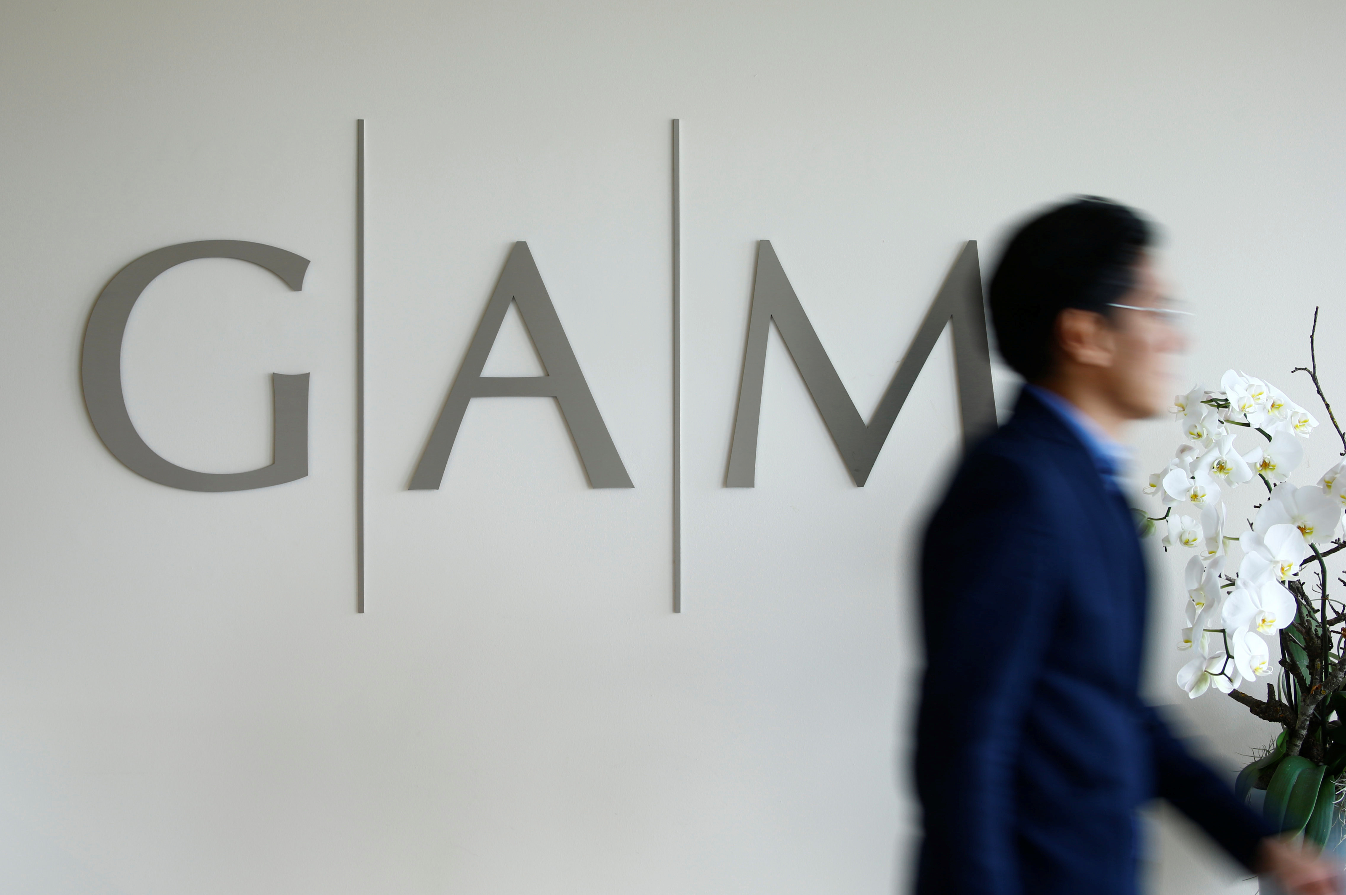 A man walks past the logo of GAM investment management company in Zurich