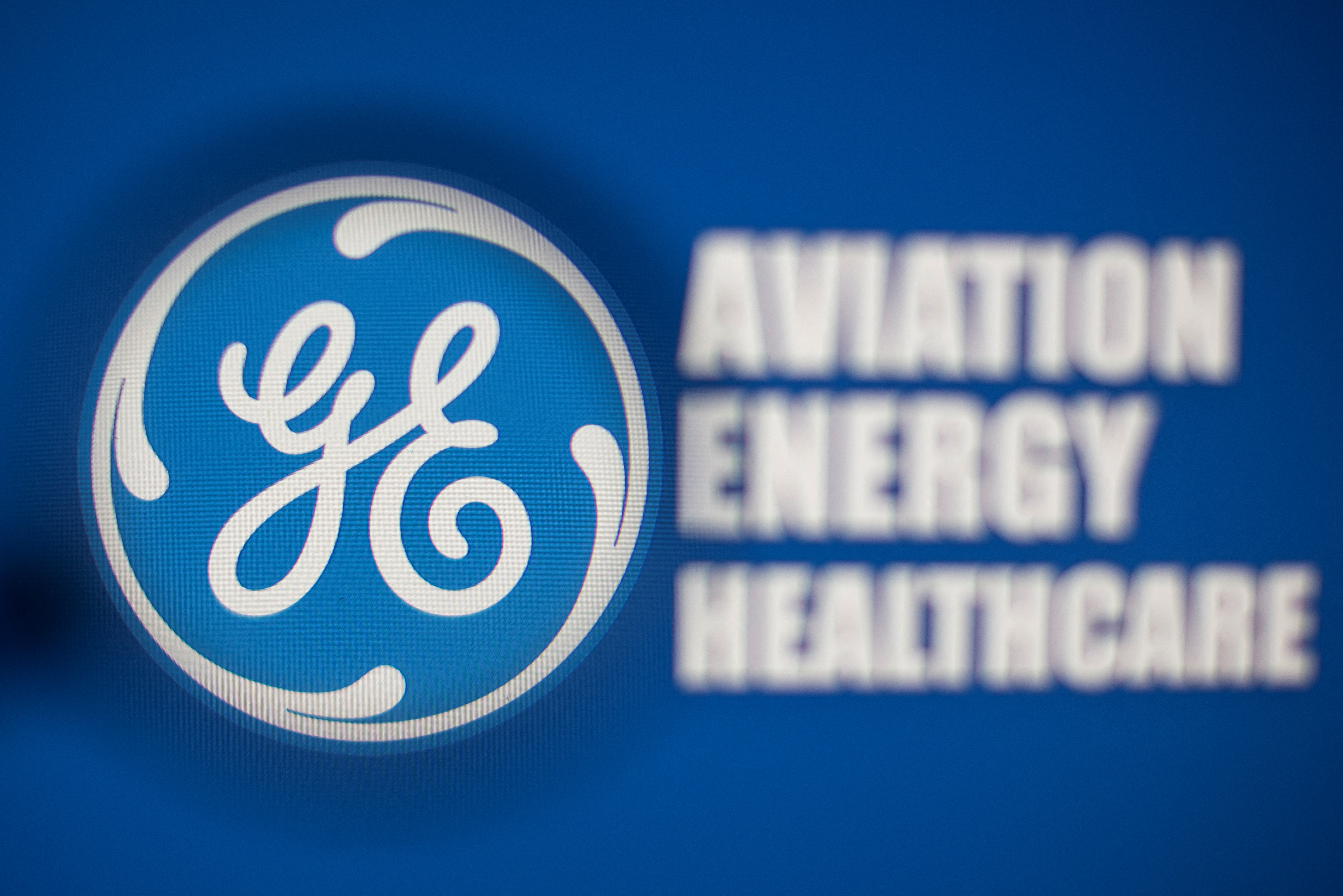 General Electric logo is seen through magnifier in front of displayed Aviation, Energy, Healthcare words in this illustration taken