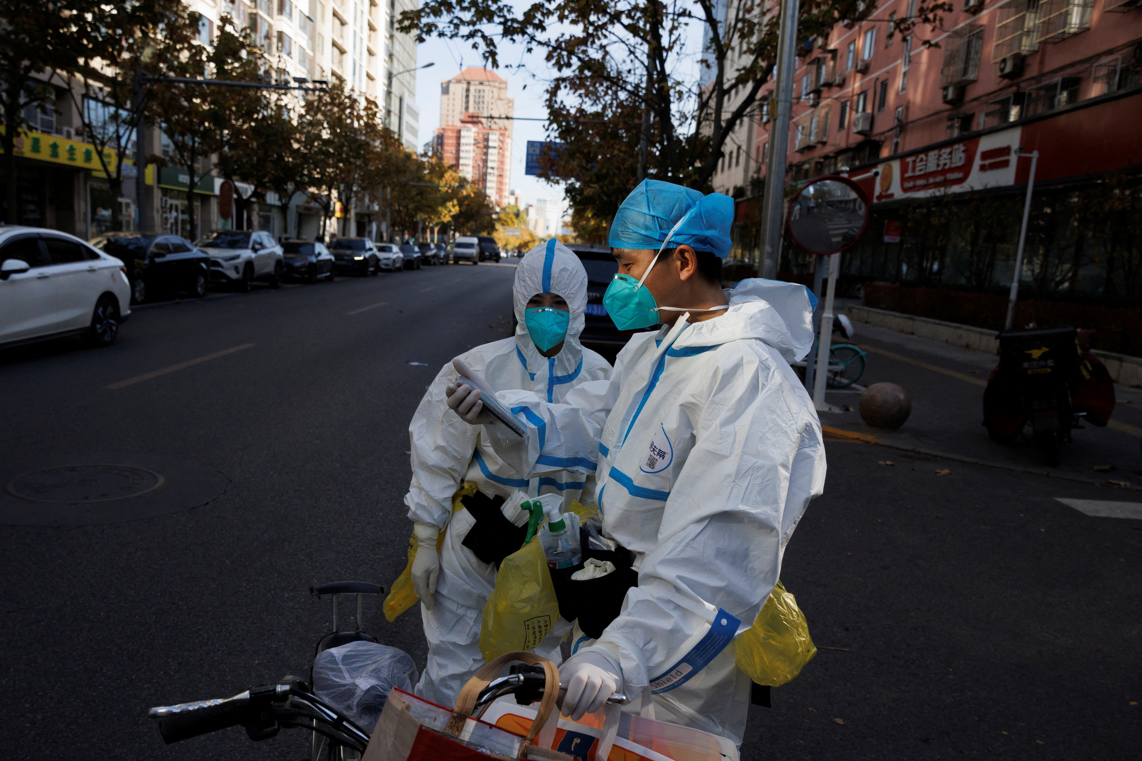Pandemic prevention workers in protective suits stand on a street as outbreaks of coronavirus disease (COVID-19) continue in Beijing