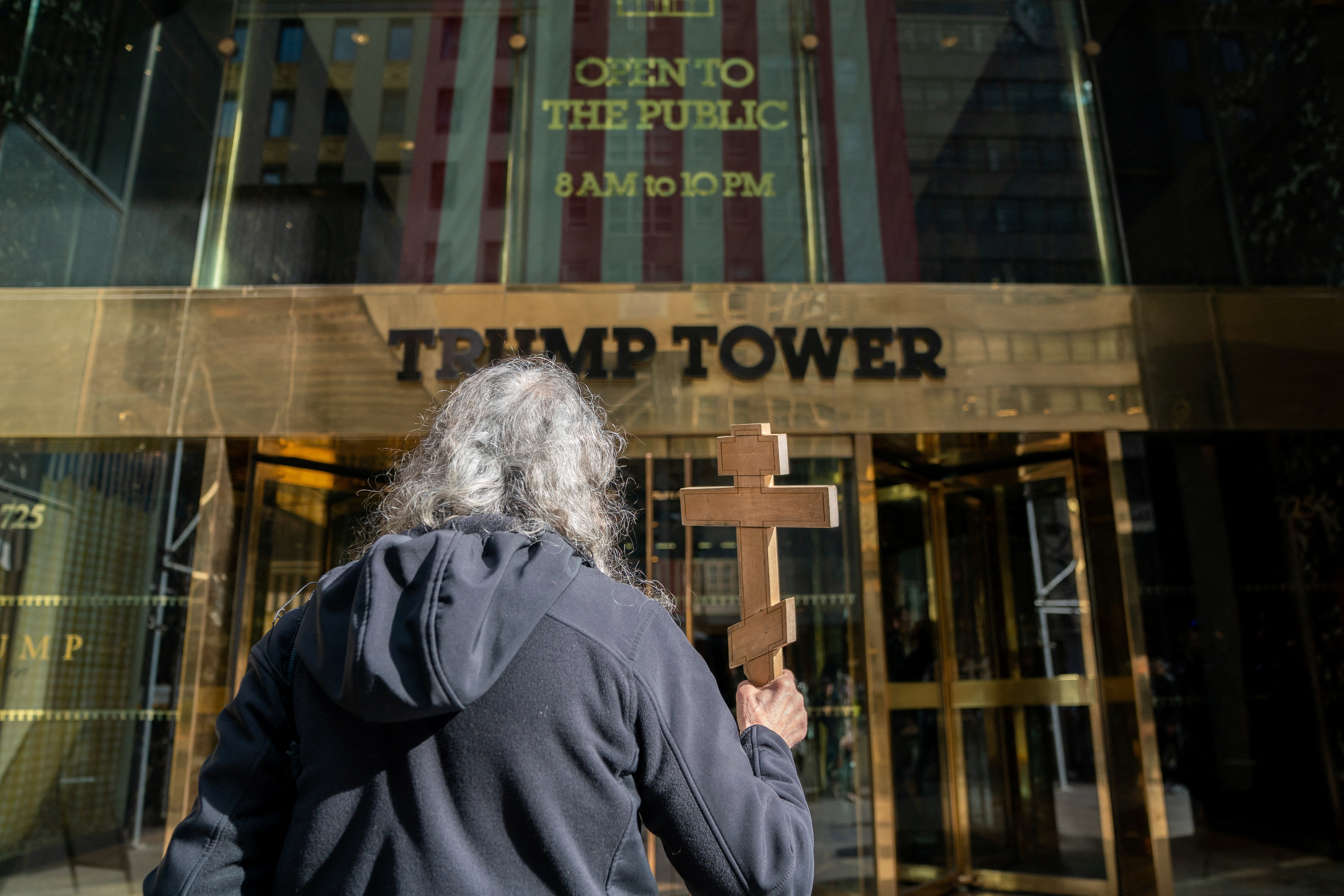 A person holds a cross outside of Trump Tower, in New York