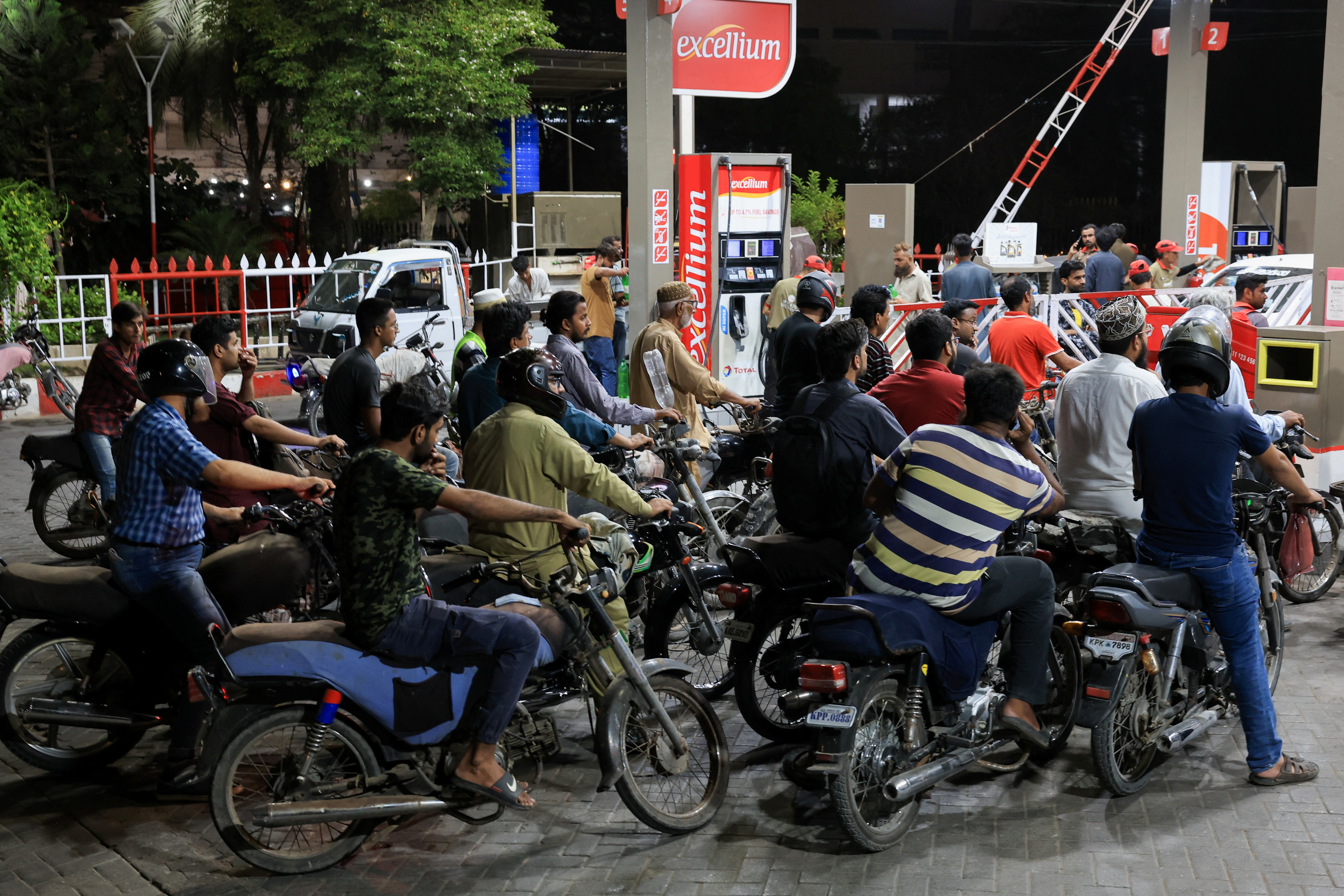 People wait for their turn to get fuel at a petrol station in Karachi