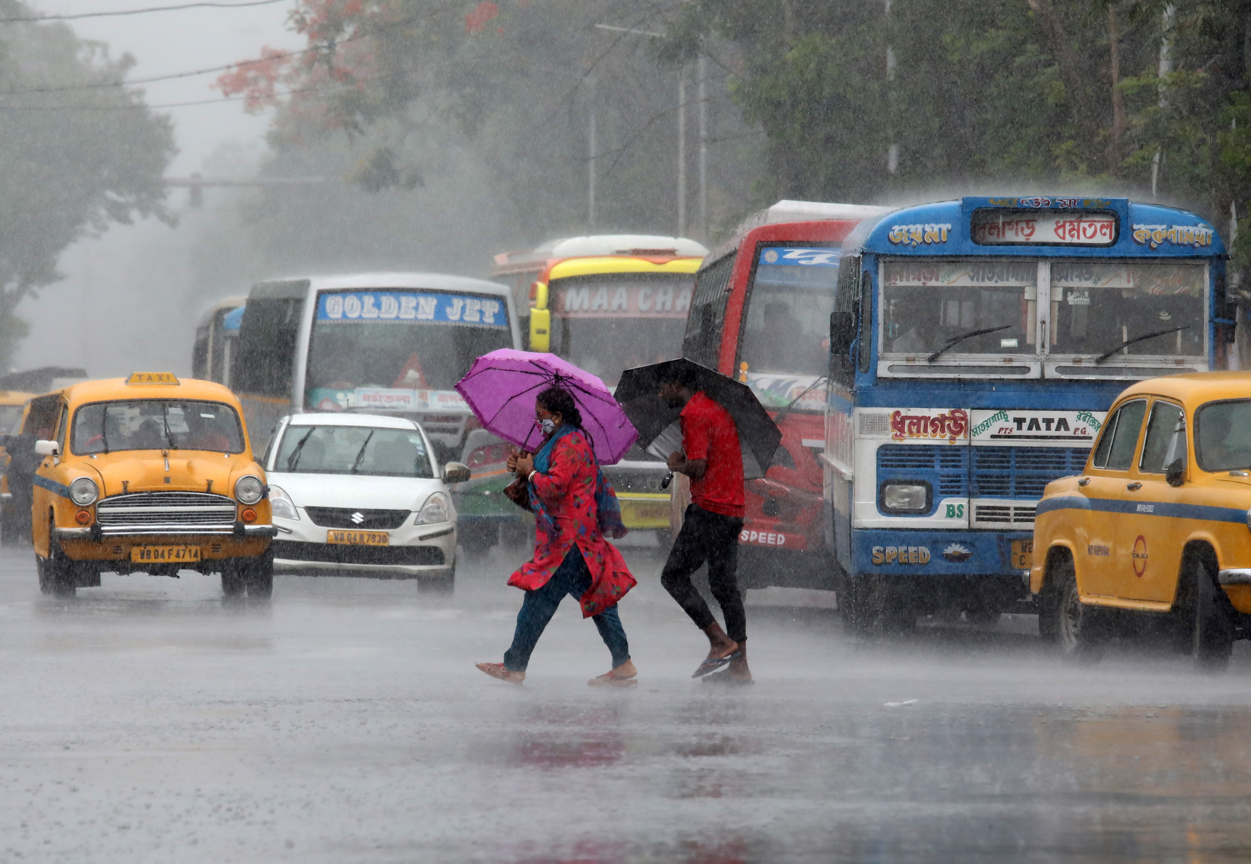 Commuters with umbrellas cross a road during heavy rains caused by Cyclone Asani, in Kolkata