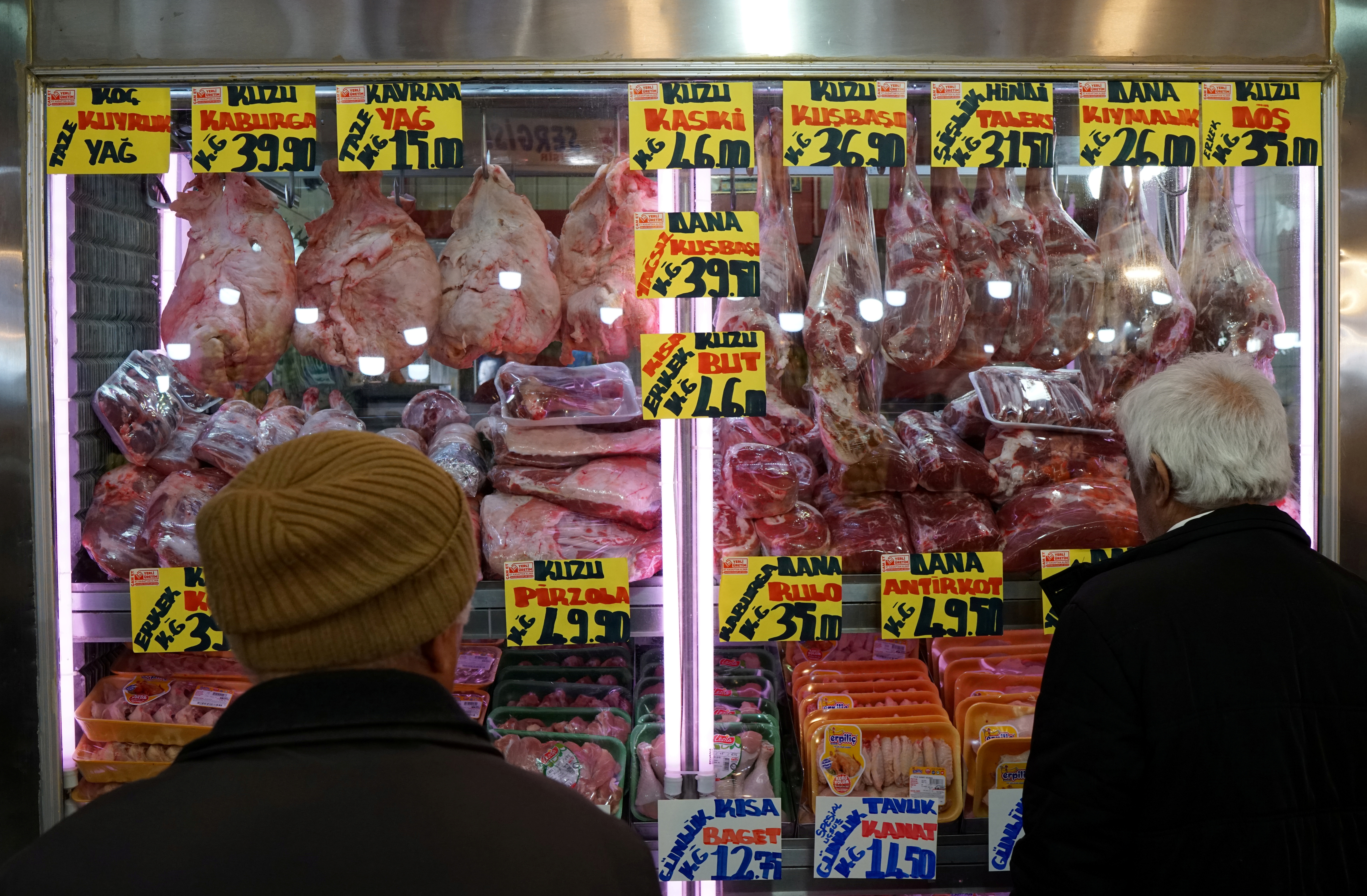 People check prices of a butcher at a bazaar in Ankara