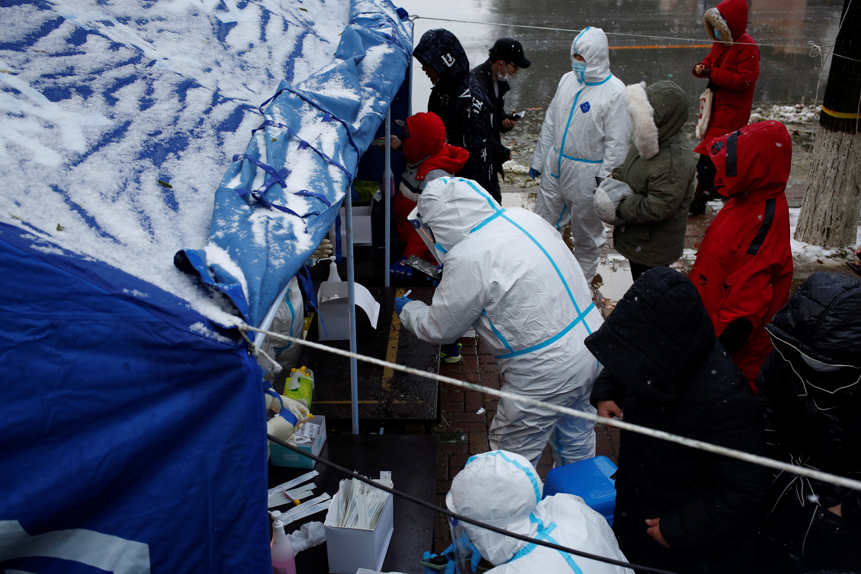 People line up for nucleic acid testing in the snow in Dalian
