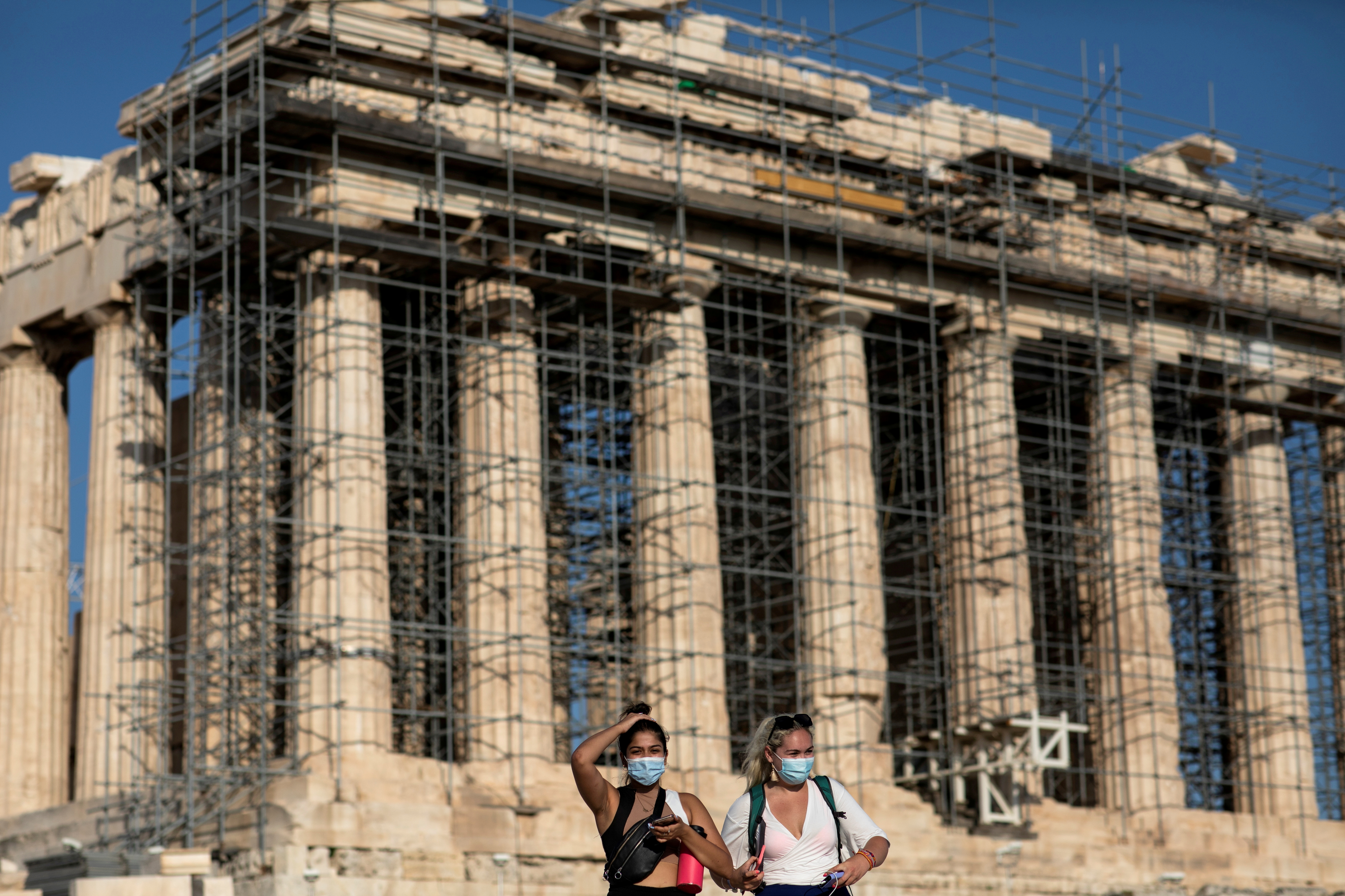 Two women wearing protective face masks amid COVID-19 pandemic visit the Parthenon temple atop the Acropolis hill in Athens, Greece, June 8, 2021. REUTERS/Alkis Konstantinidis/File Photo