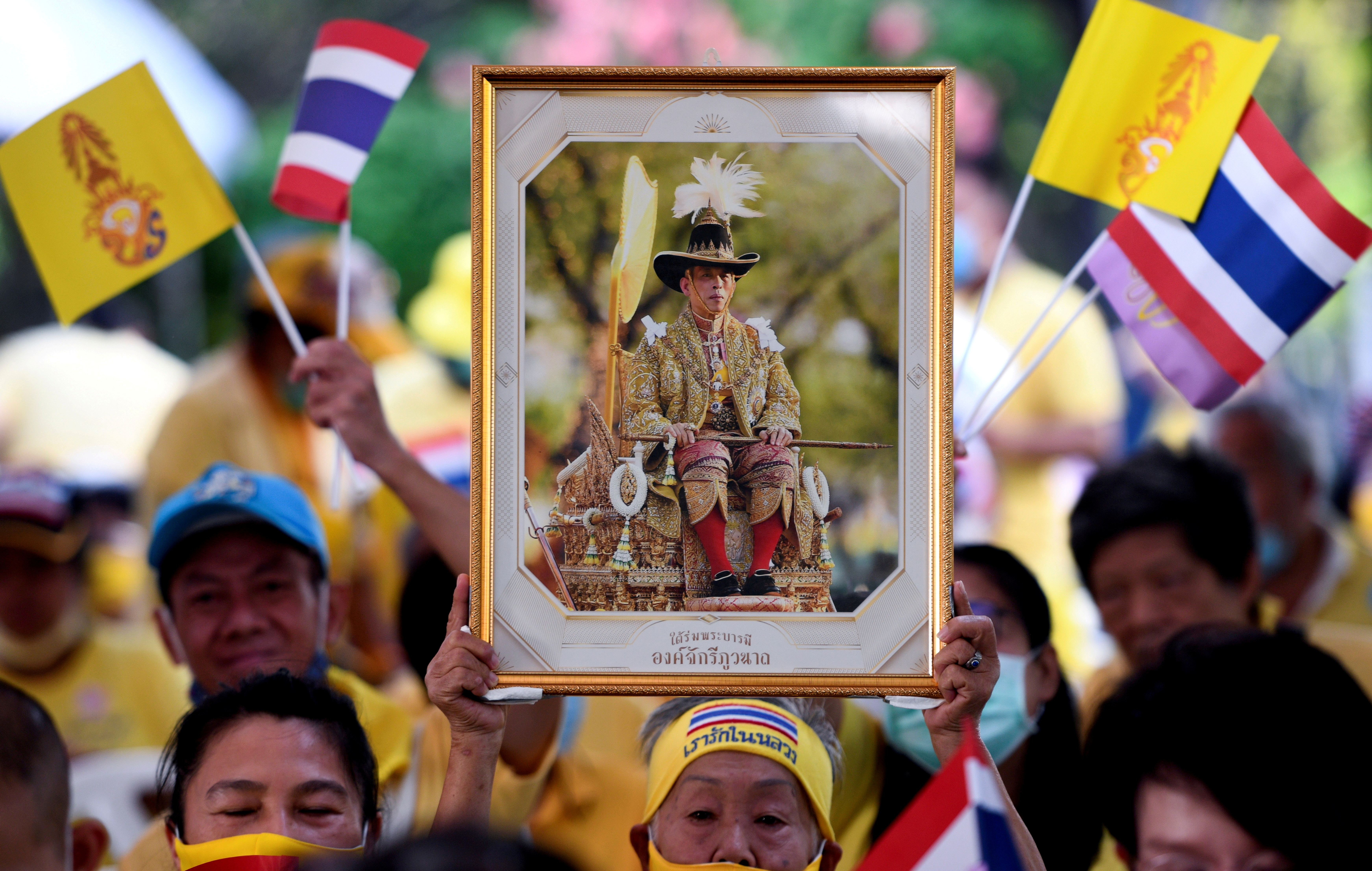 A person holds a portrait of Thailand's King Maha Vajiralongkorn, as royalists wait for the arrival of royal couple, in Bangkok, Thailand, November 25, 2020