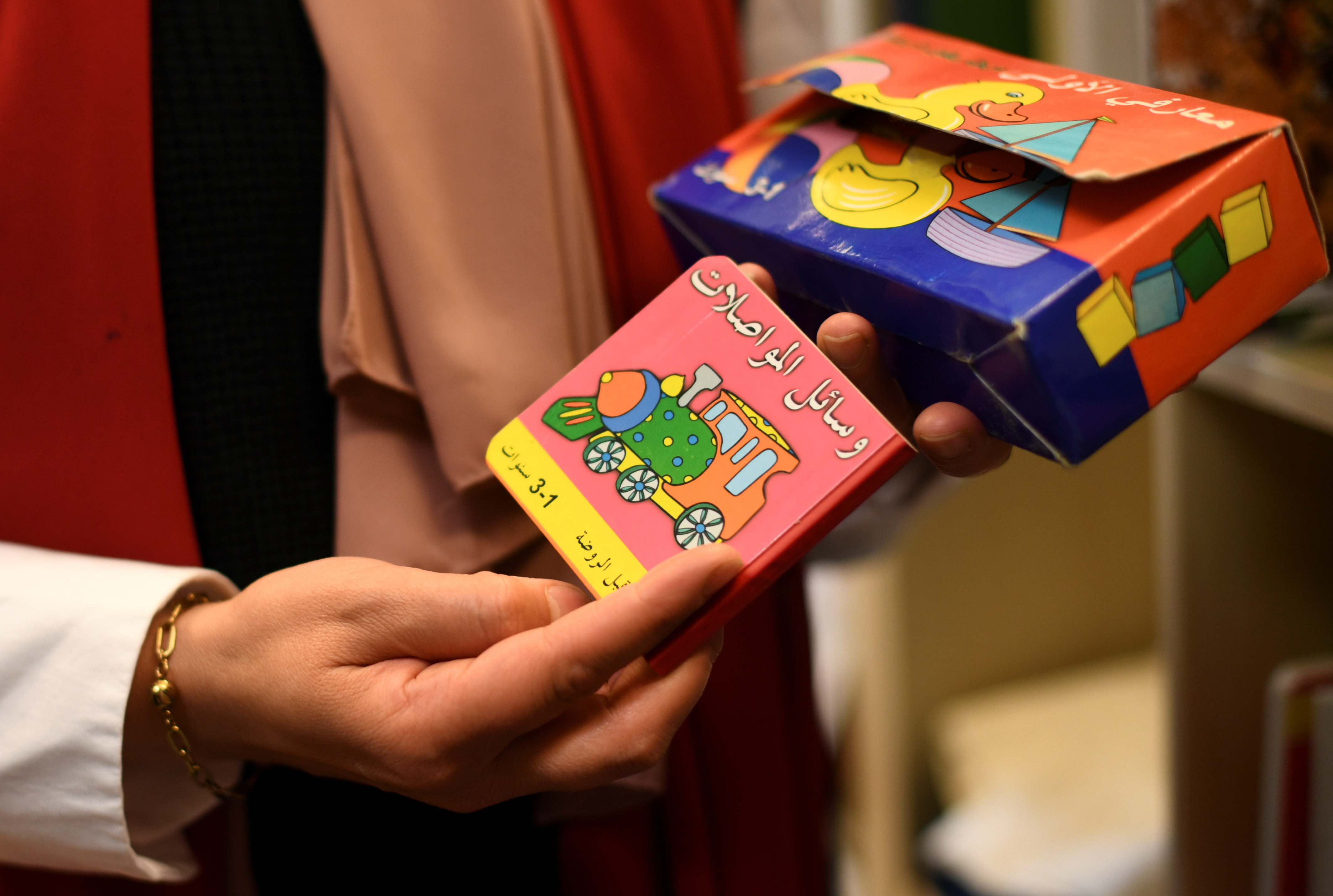 A foreign language children's book is pictured in the hands of Social worker Noor Zayed of the Stadtteilmuetter migrant integration project run by Protestant charity Diakonie in Berlin's district of Neukoelln, Germany May 4, 2021. Picture taken May 4, 2021.  REUTERS/Annegret Hilse
