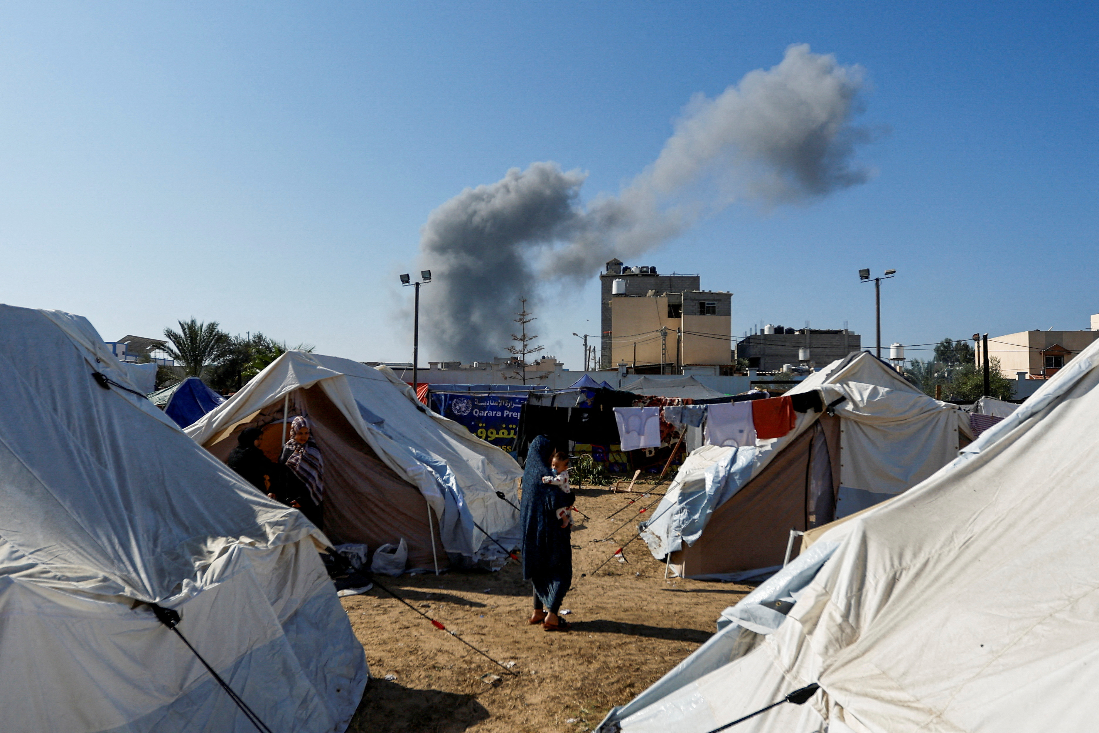 Smoke rises from nearby Israeli strikes as seen from a tent camp sheltering displaced Palestinians, in Khan Younis