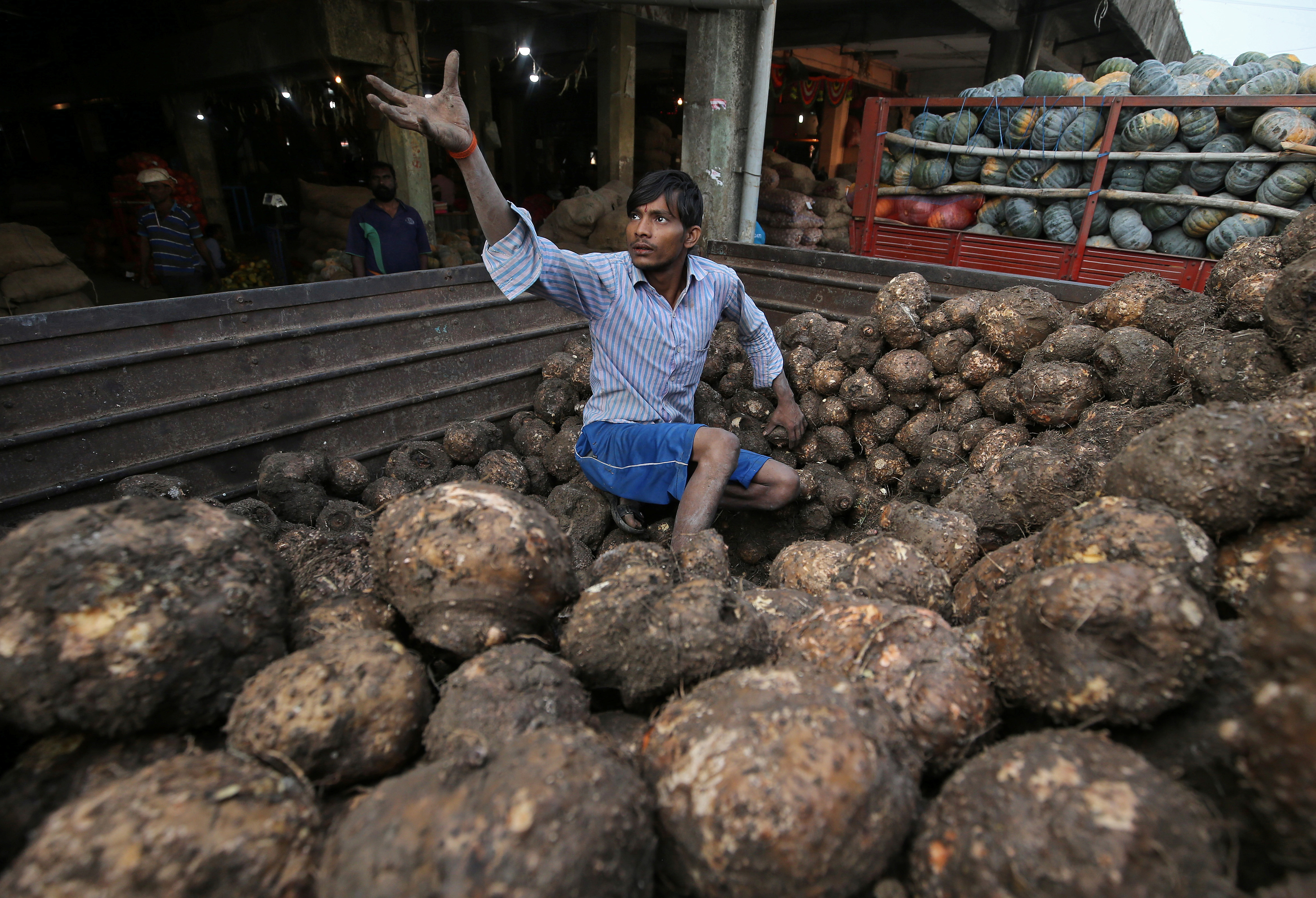 A man sorts yams in a supply truck at a wholesale market in Mumbai