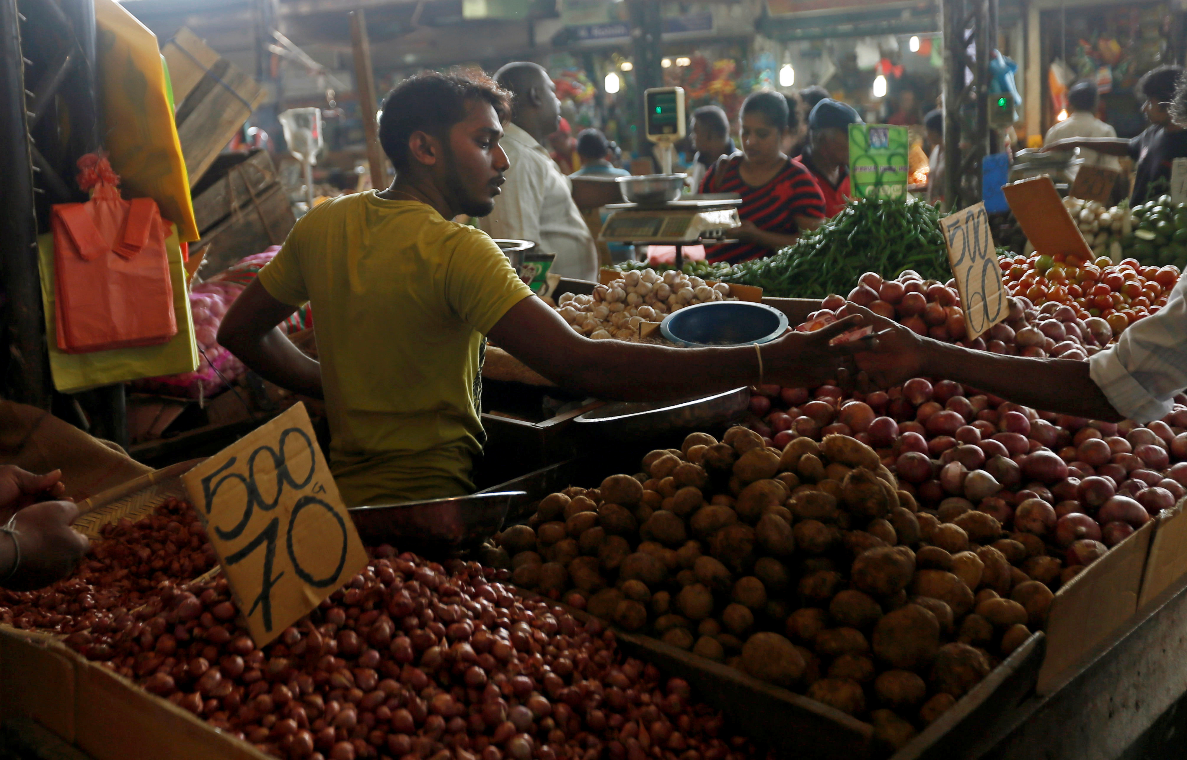 A vendor of a stall exchanges money with a customer at a main market in Colombo, Sri Lanka