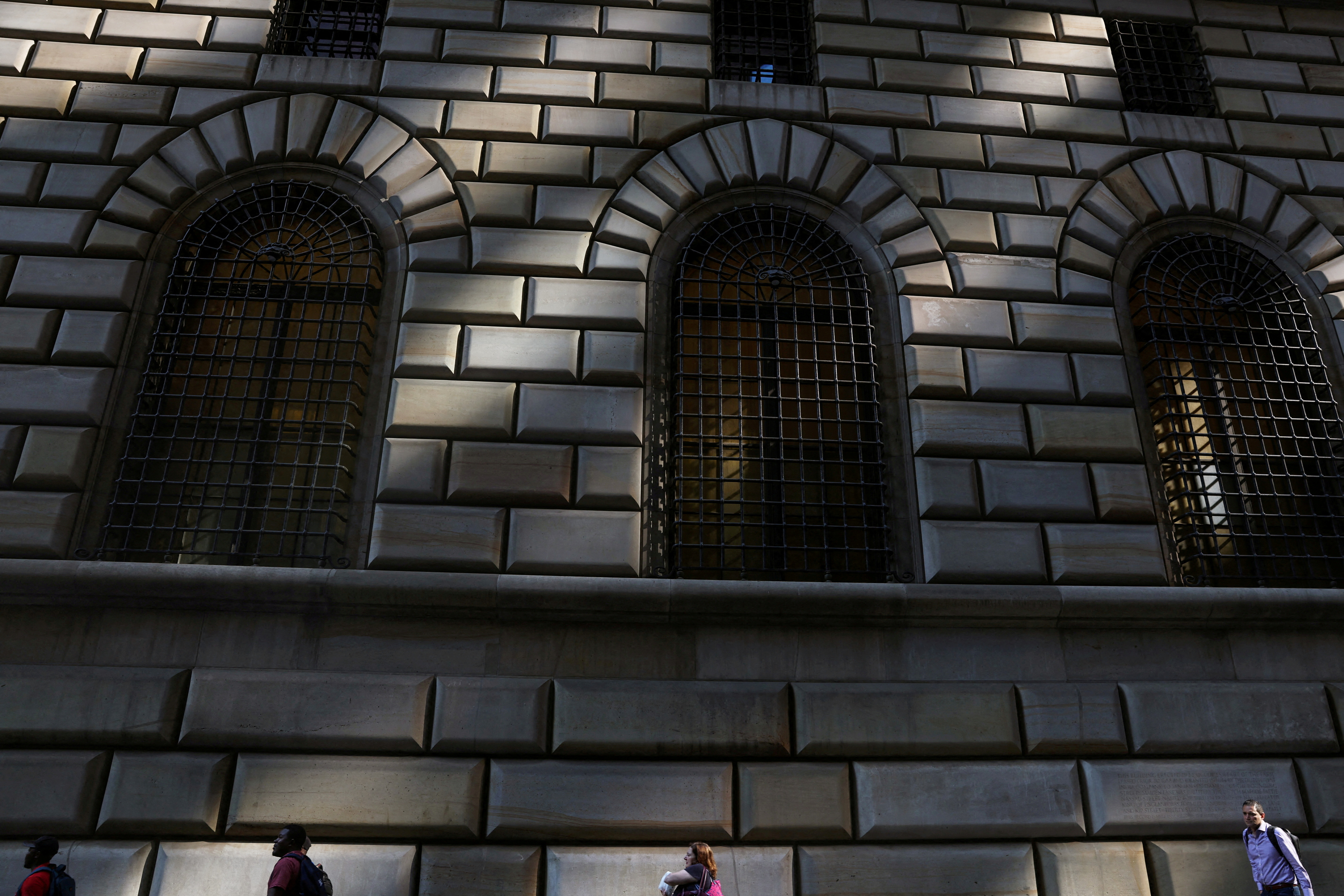 People walk by the Federal Reserve Bank of New York in the financial district of New York City