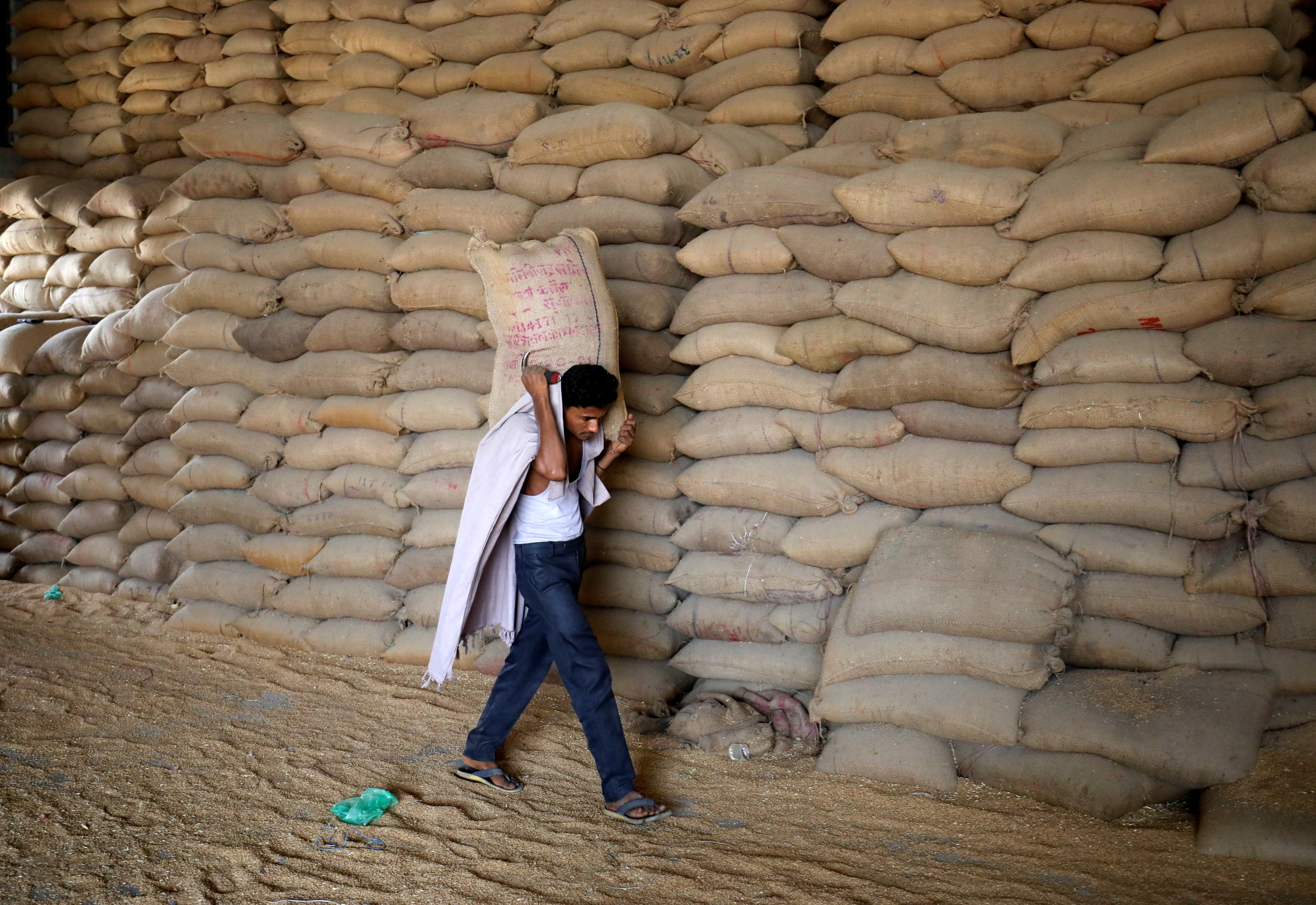 Un trabajador carga un saco de trigo para tamizarlo en un molino de granos en las afueras de Ahmedabad.