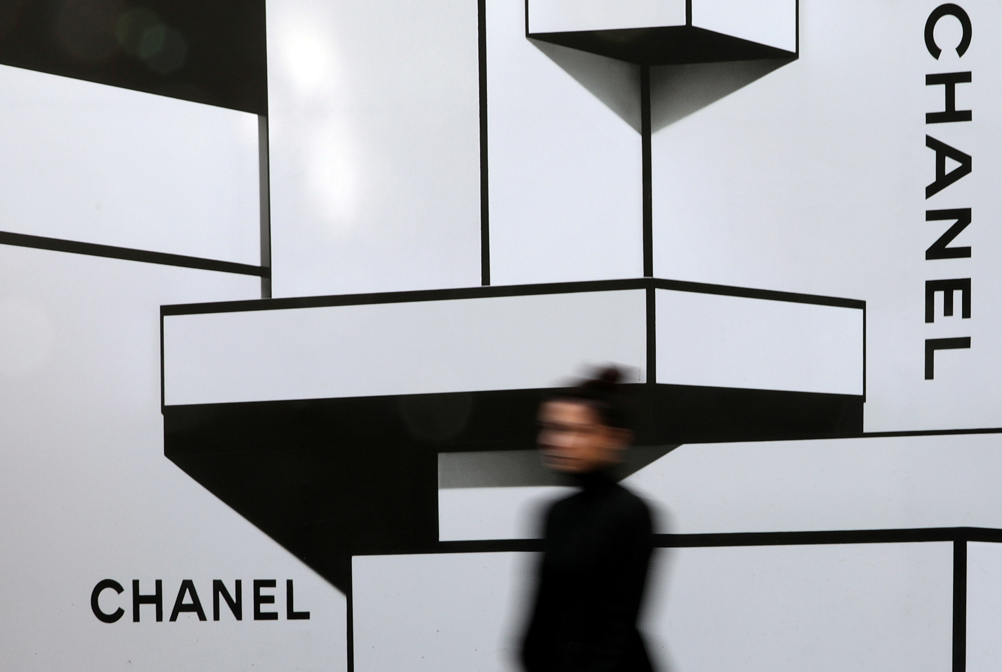 A woman walks past a wall with logos of French luxury goods maker Chanel in Nice, France, February 22, 2017. REUTERS/Eric Gaillard/File Photo