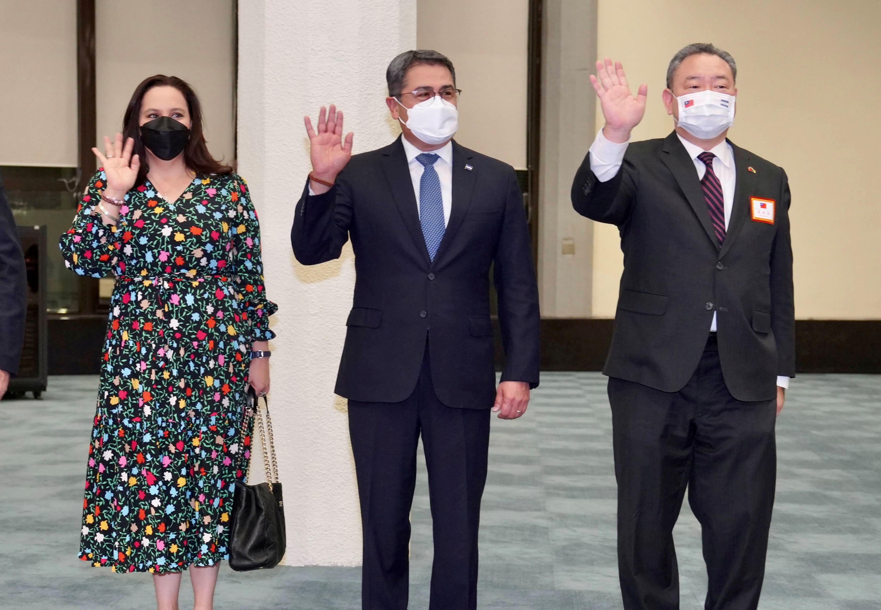 Honduran President Juan Orlando Hernandez and his wife Ana Garcia, wave to the media next to Alexander Tah-ray Yui, Taiwan's Vice Minister of Foreign Affairs, upon their arrival at Taoyuan International Airport in Taoyuan, Taiwan, November 12, 2021. Taiwan Ministry of Foreign Affairs/Handout via REUTERS