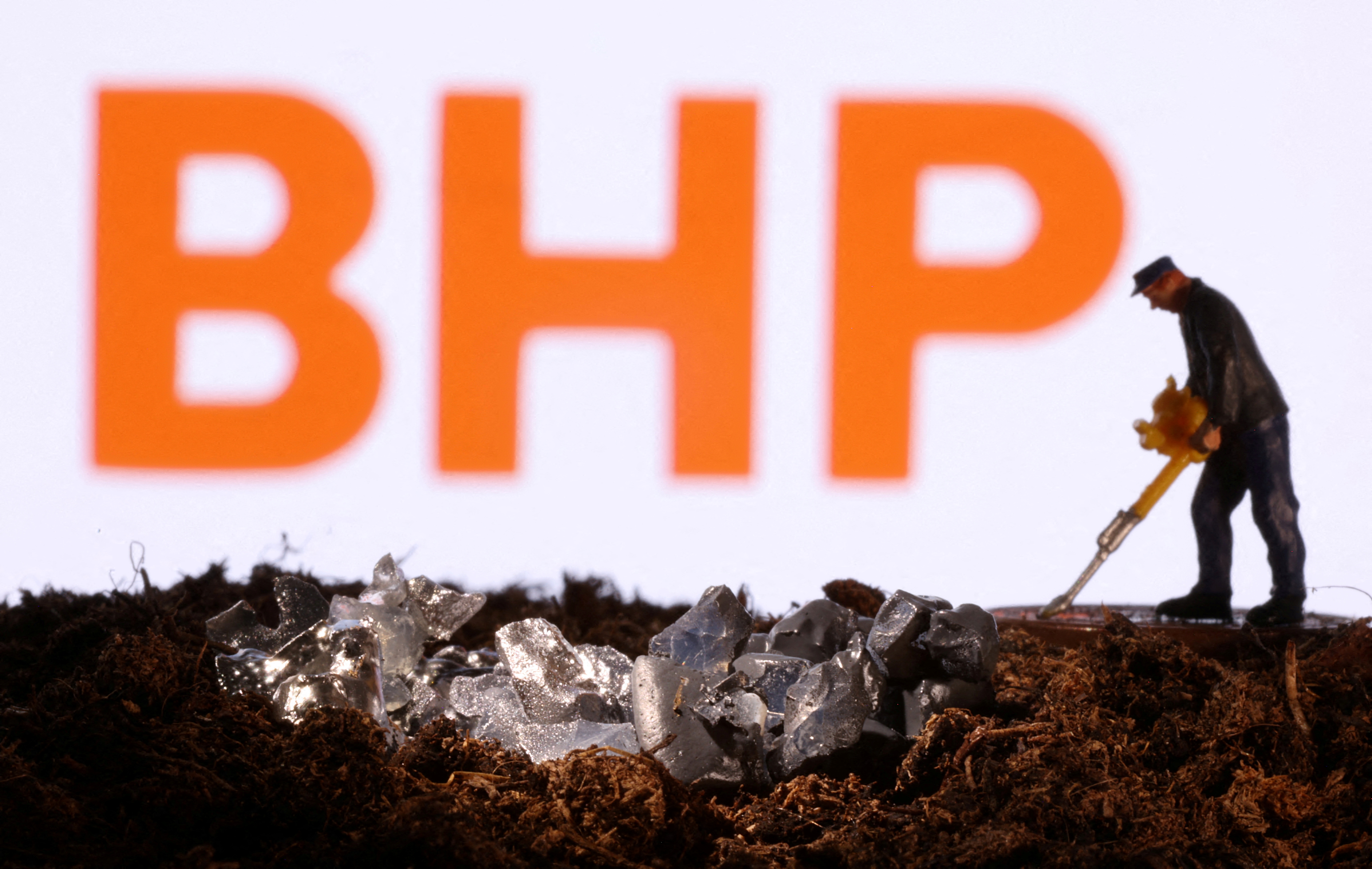 Small toy figure and mineral imitation are seen in front of the BHP logo in this illustration