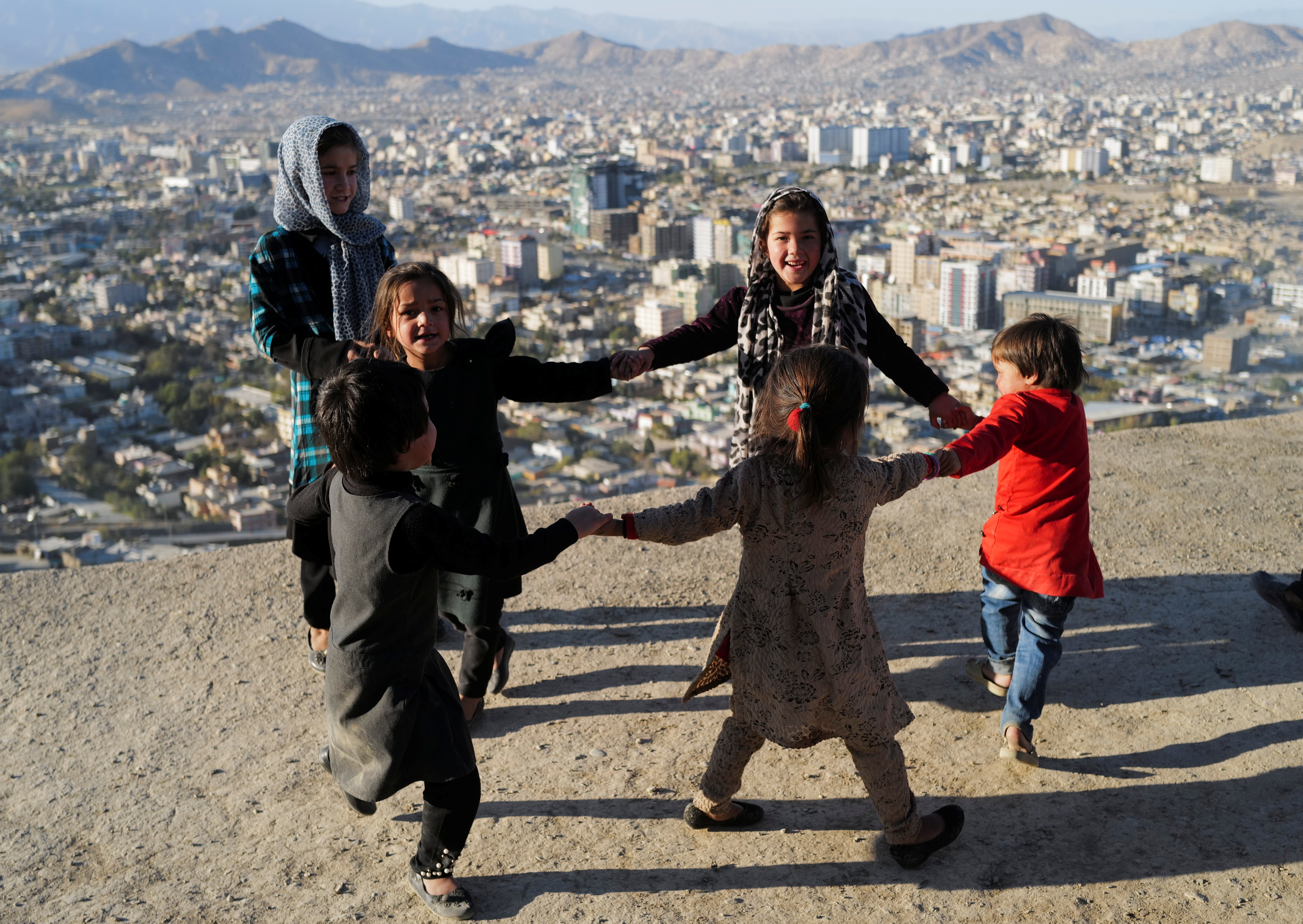 Children play outside their house at Tv mountain in Kabul