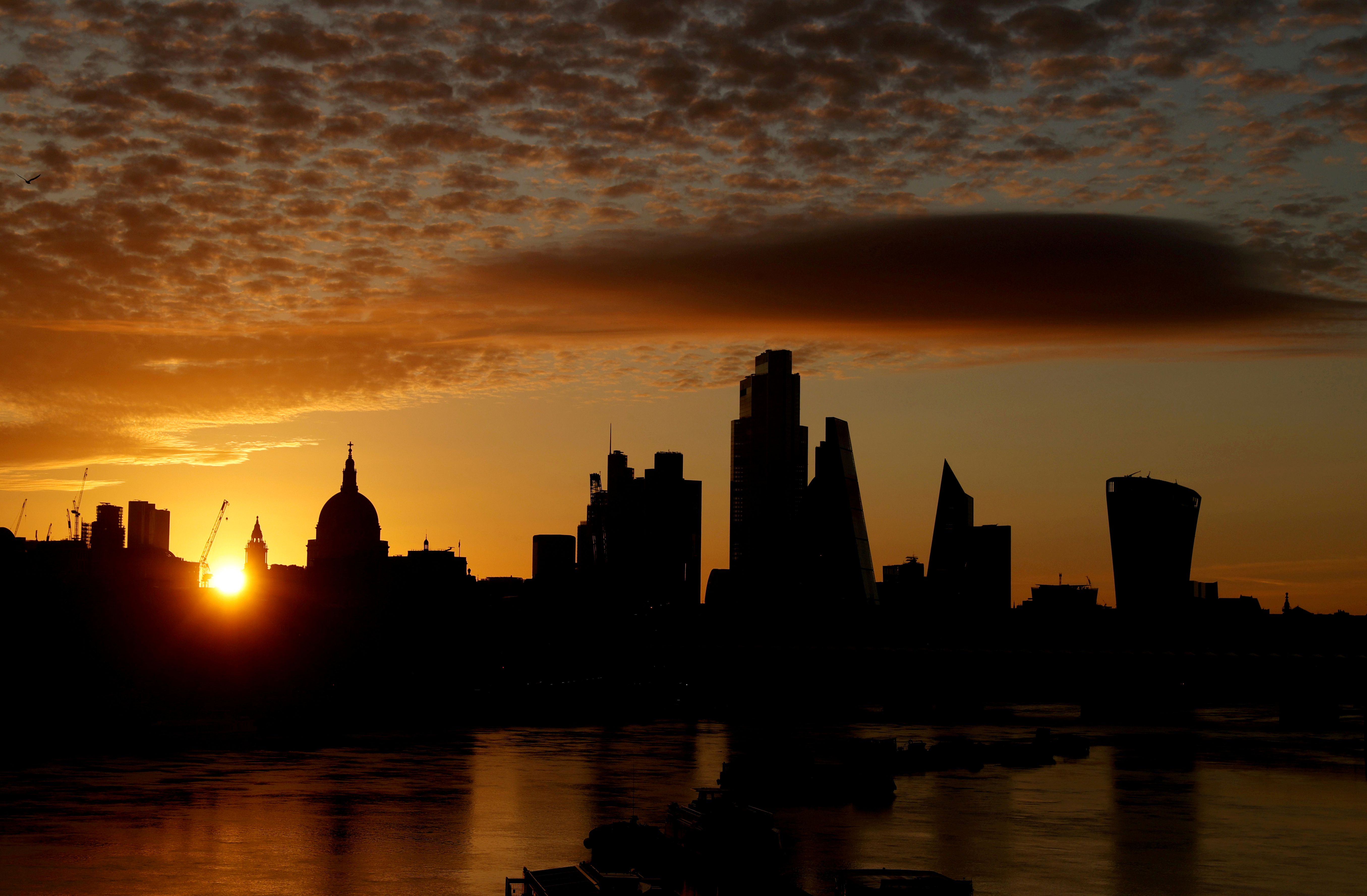 FILE PHOTO: The sun rises behind the skyline of St Paul's Cathedral and the City of London, in London