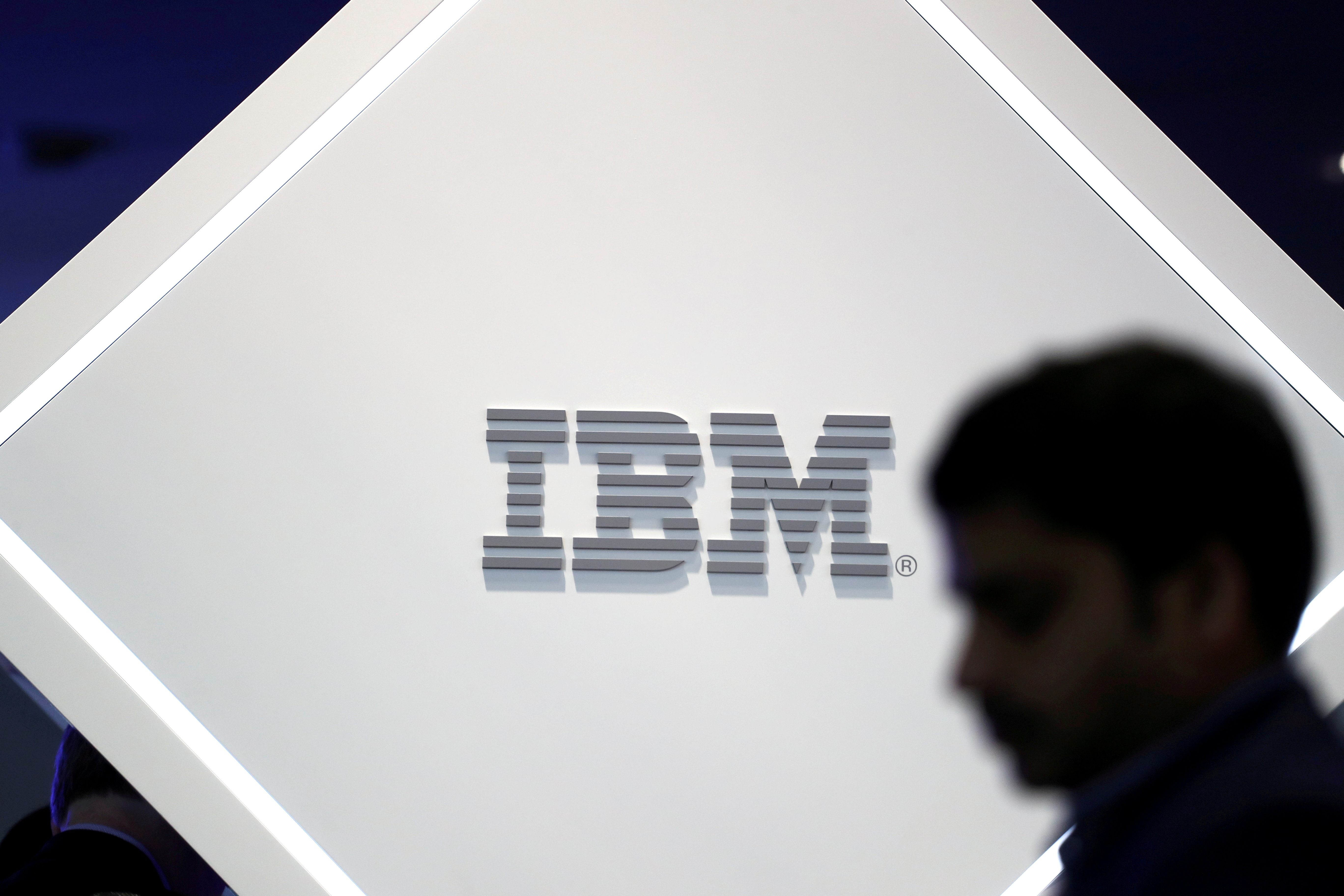 FILE PHOTO: A man stands near an IBM logo at the Mobile World Congress in Barcelona, Spain, February 25, 2019. REUTERS/Sergio Perez/File Photo