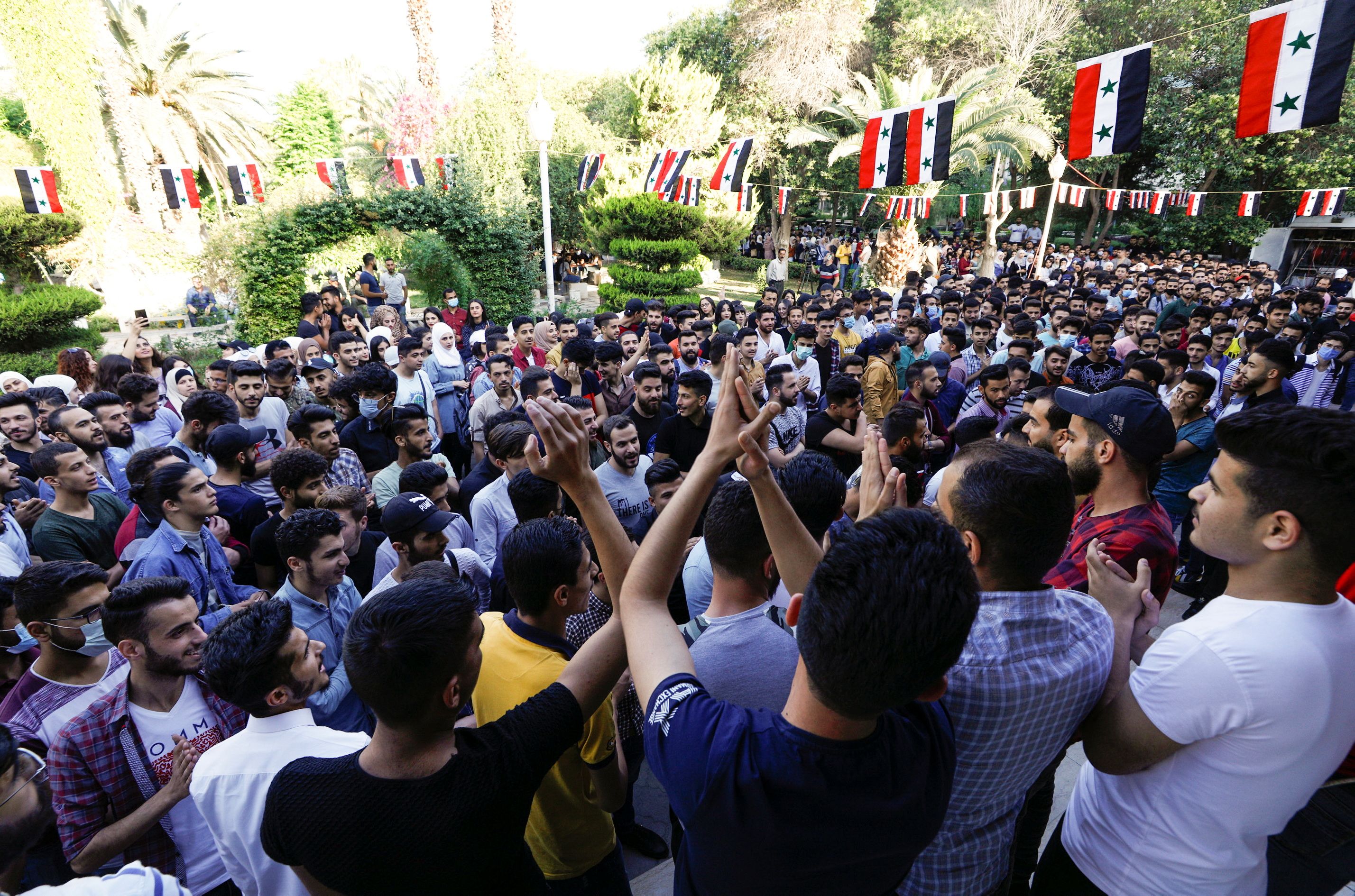 Students gesture as they wait outside a polling station before the polls open for the presidential elections, in Damascus