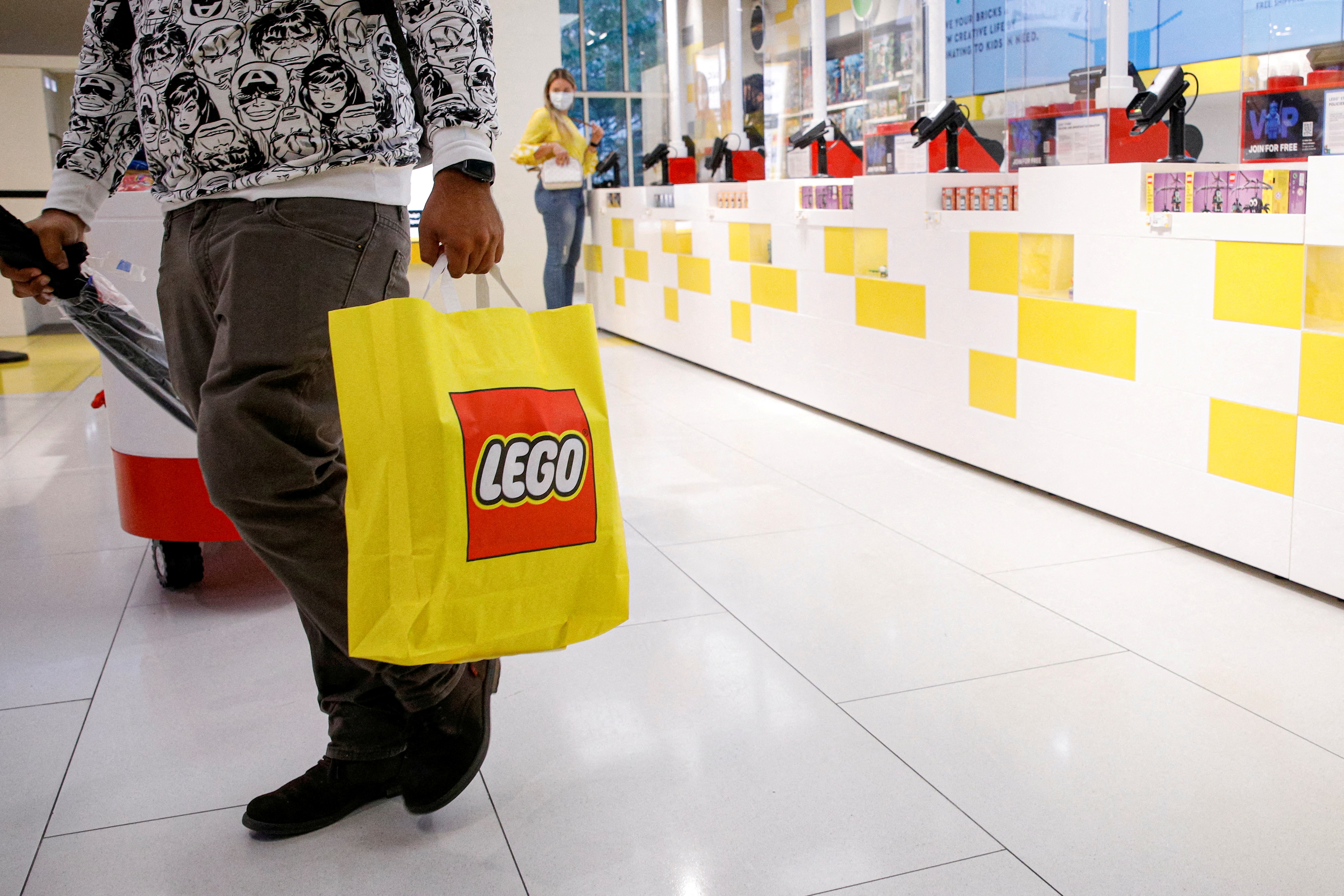 A customer carries a bag while shopping in the 5th Avenue Lego store in New York