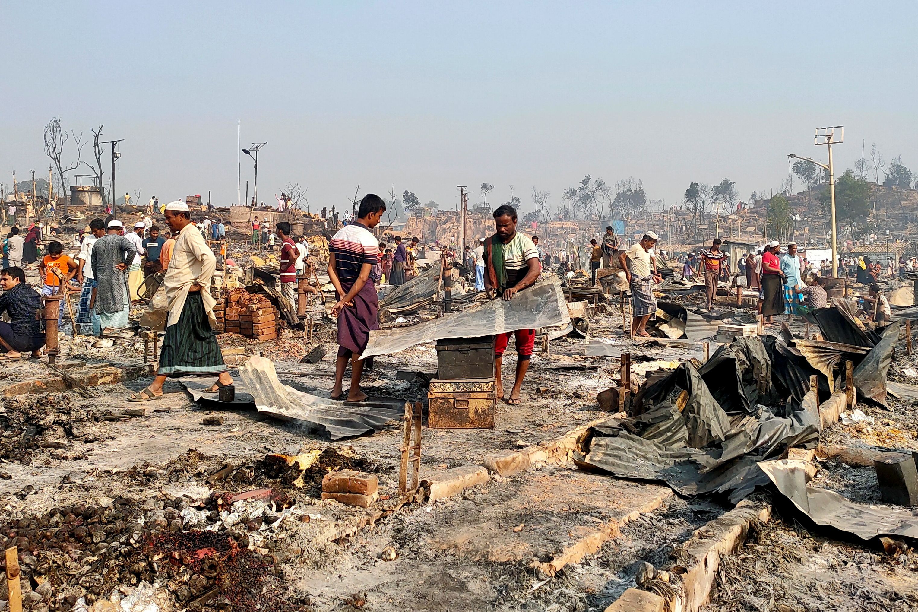 Rohingya refugees sift through rubble at the site where their shelter has been burned down following a fire that broke out at a Rohingya refugee camp in Cox's Bazar, Bangladesh, March 23, 2021. REUTERS/Ro Yassin Abdumonab 