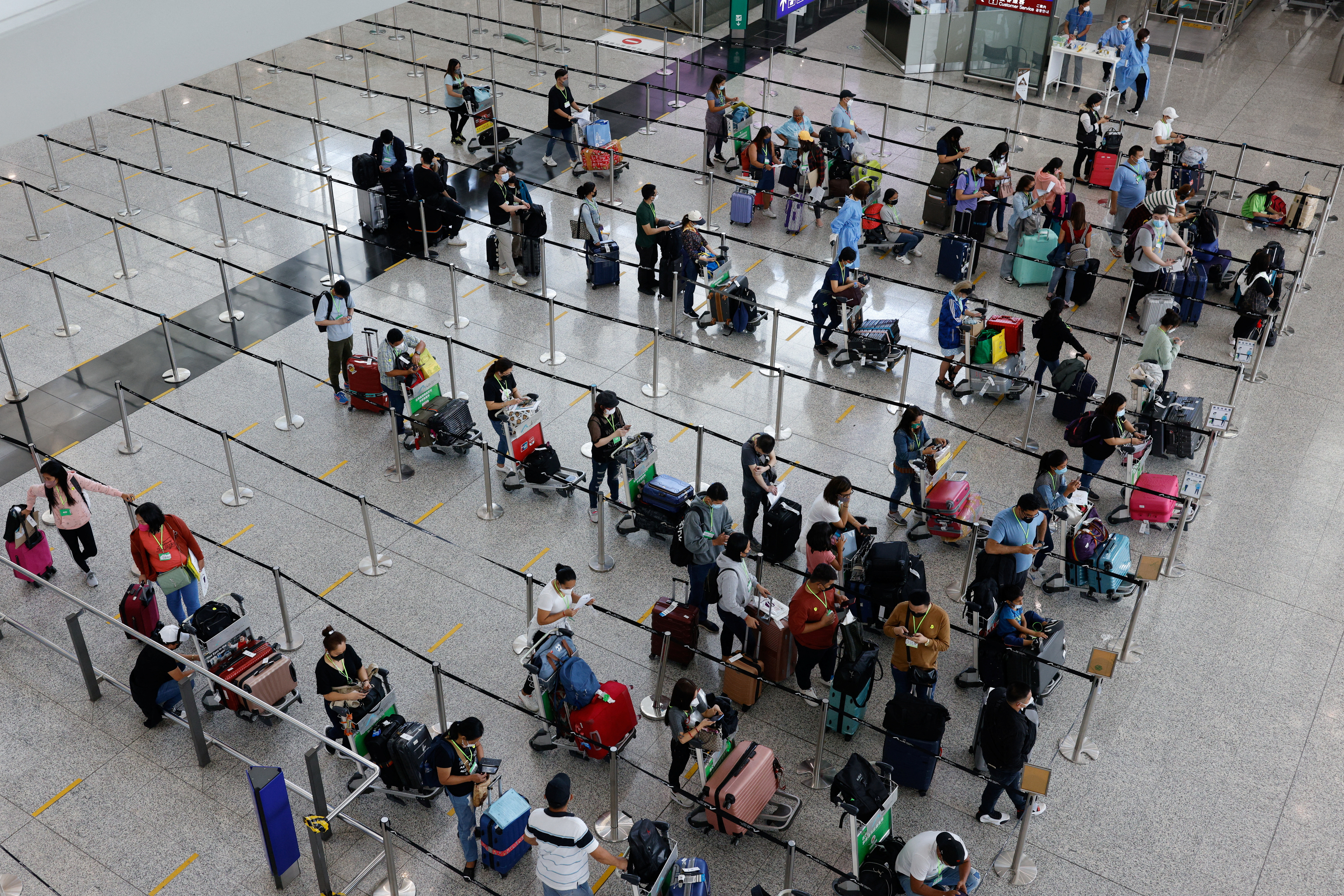 Travellers queue up for shuttle bus to quarantine hotels at the Hong Kong International Airport, amid the coronavirus disease (COVID-19) pandemic, in Hong Kong