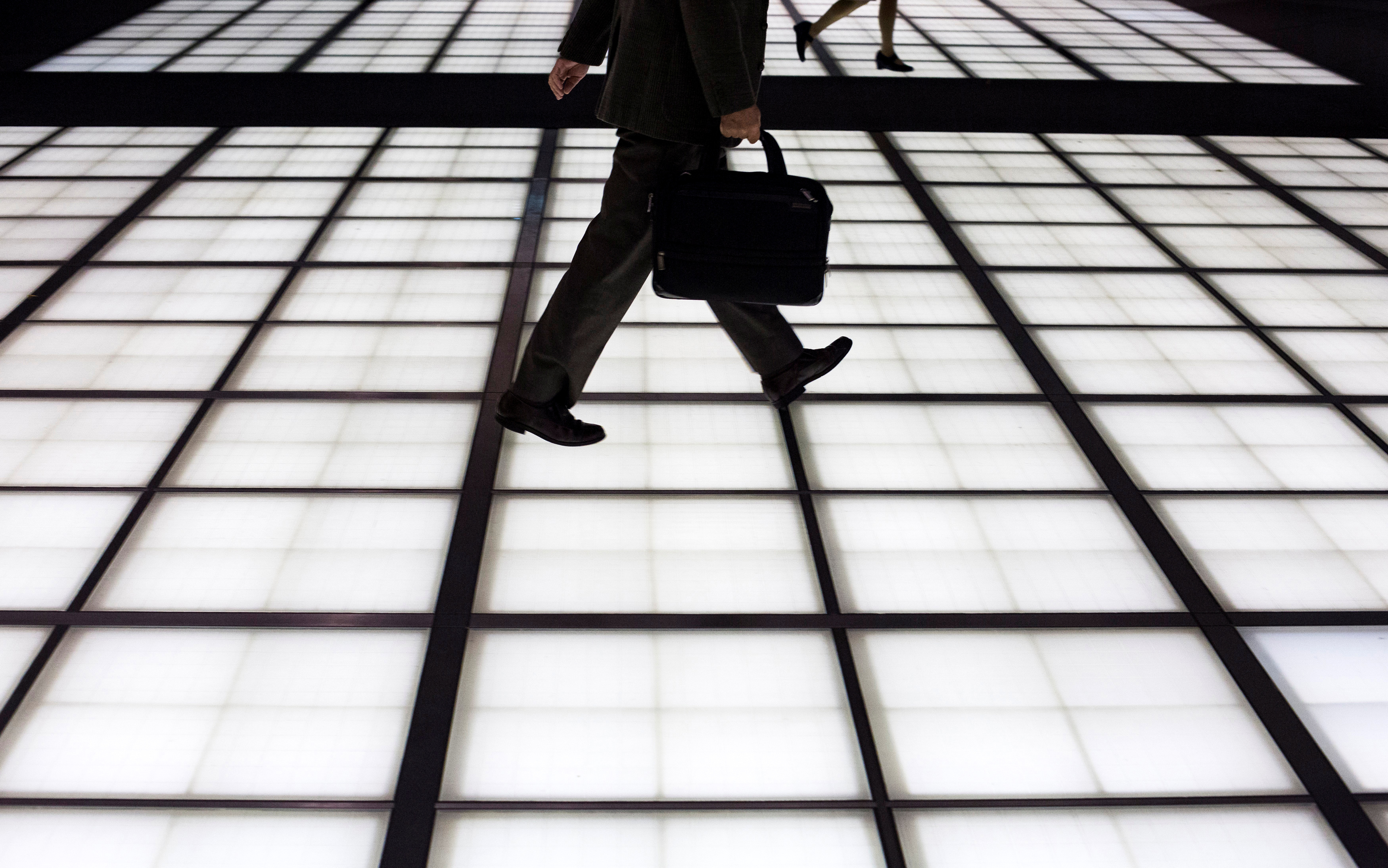 People cross an illuminated floor at a banking district in central Tokyo