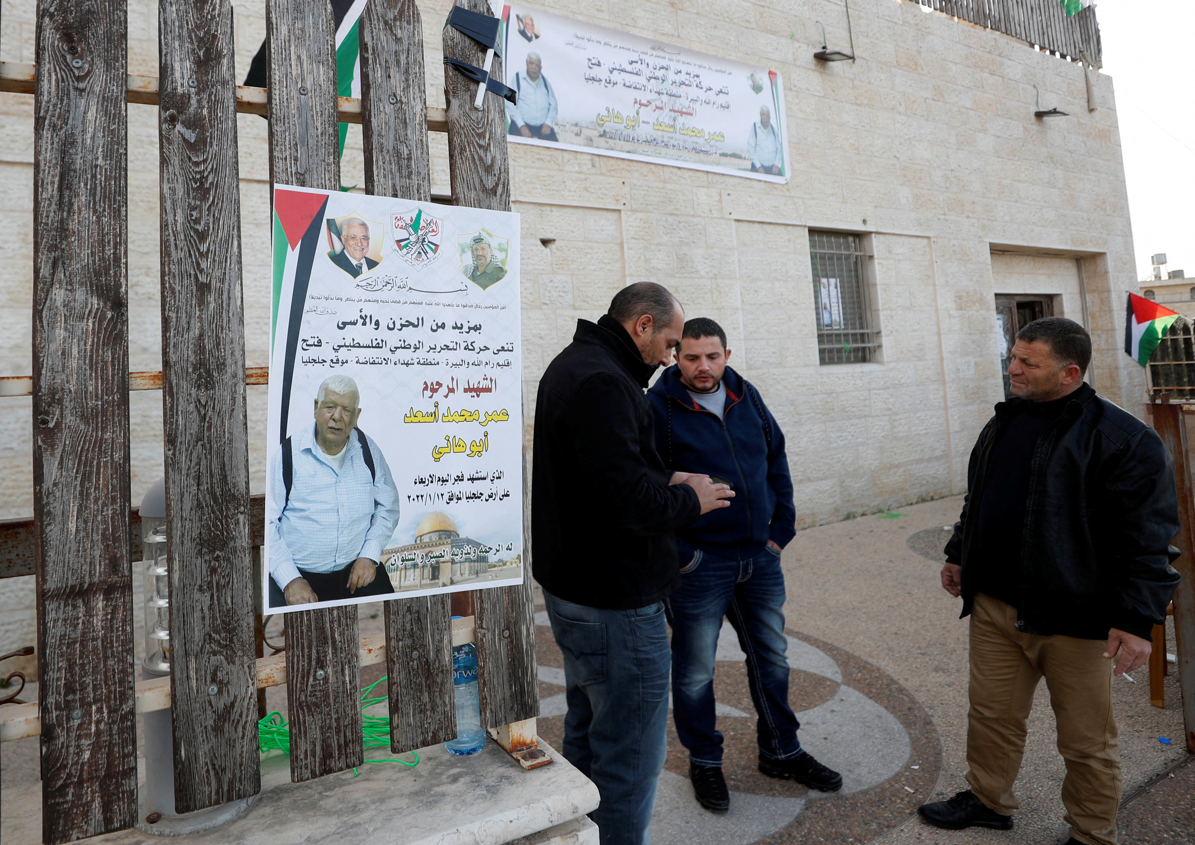 Men stand next to a poster of Palestinian Omar Abdalmajeed As'ad, 80, in Jiljilya village in the Israeli-occupied West Bank