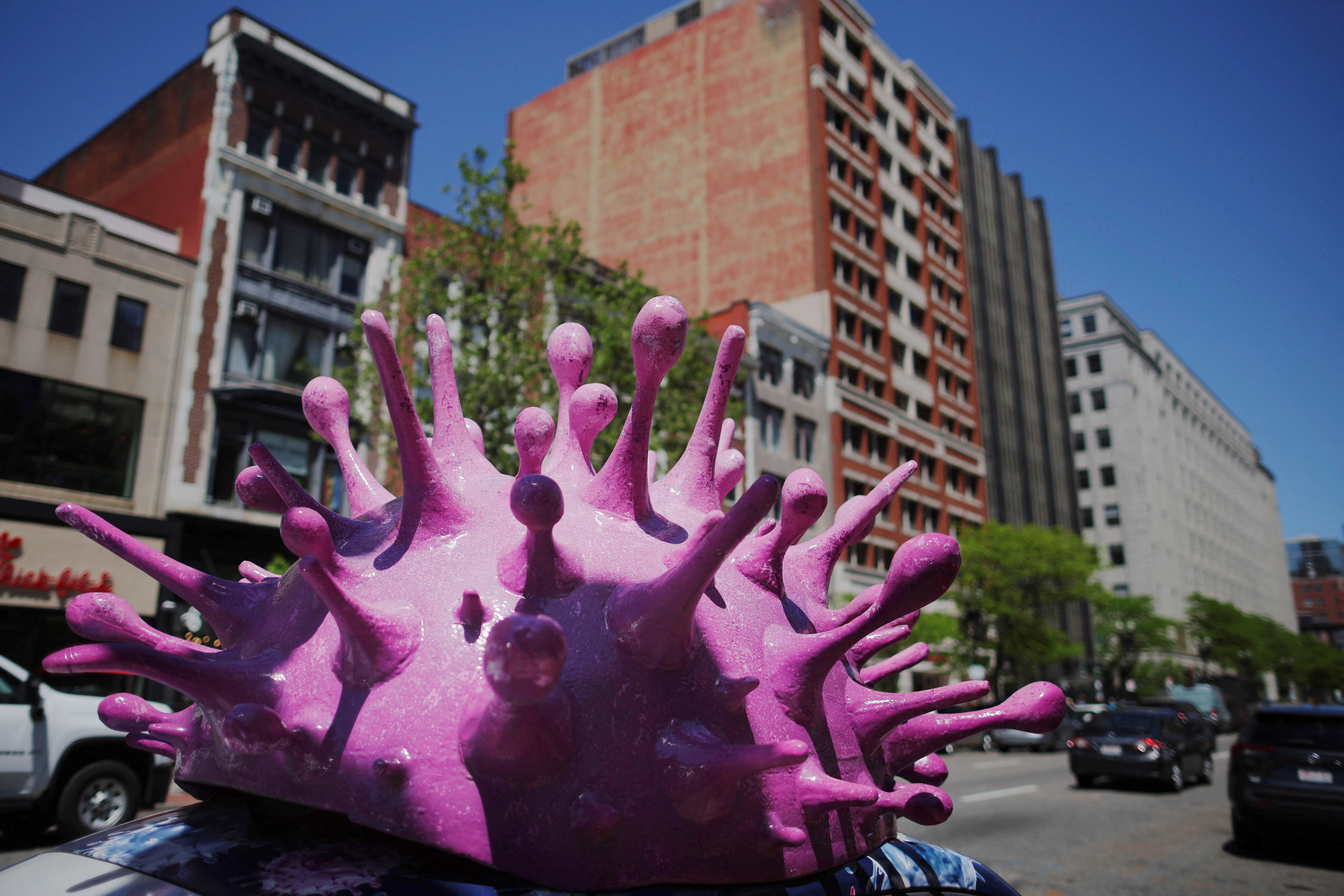 A model of a coronavirus virion sits on top of a car advertising home test kits for COVID-19 in Boston, Massachusetts