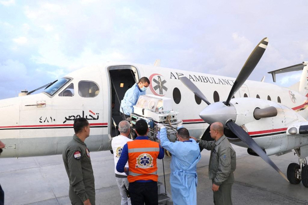Médicos transportam um bebê palestino prematuro evacuado de Gaza, no lado egípcio, no aeroporto Al-Arish
