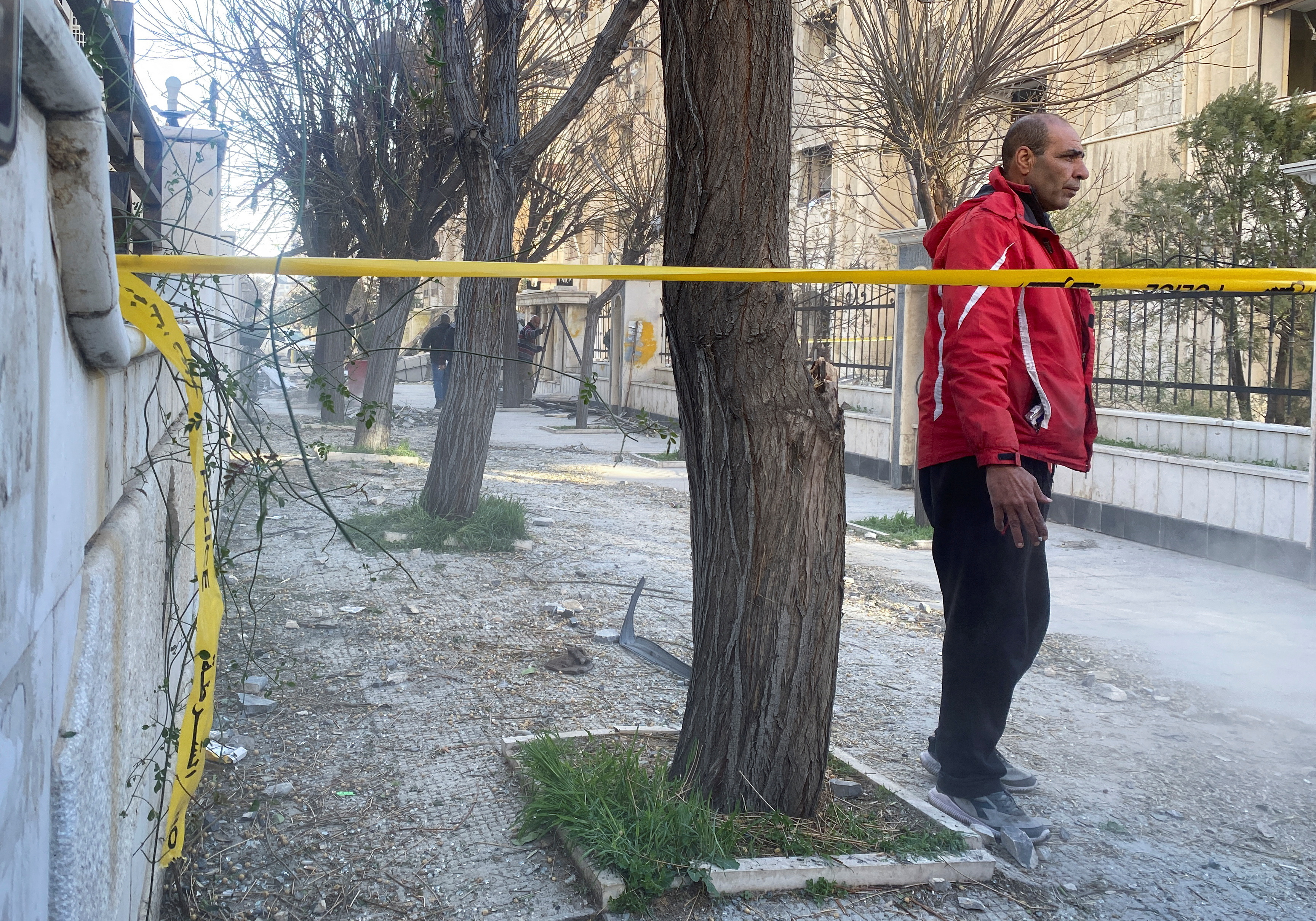 A man stands near the site of a rocket attack, in central Damascus' Kafr Sousa neighborhood