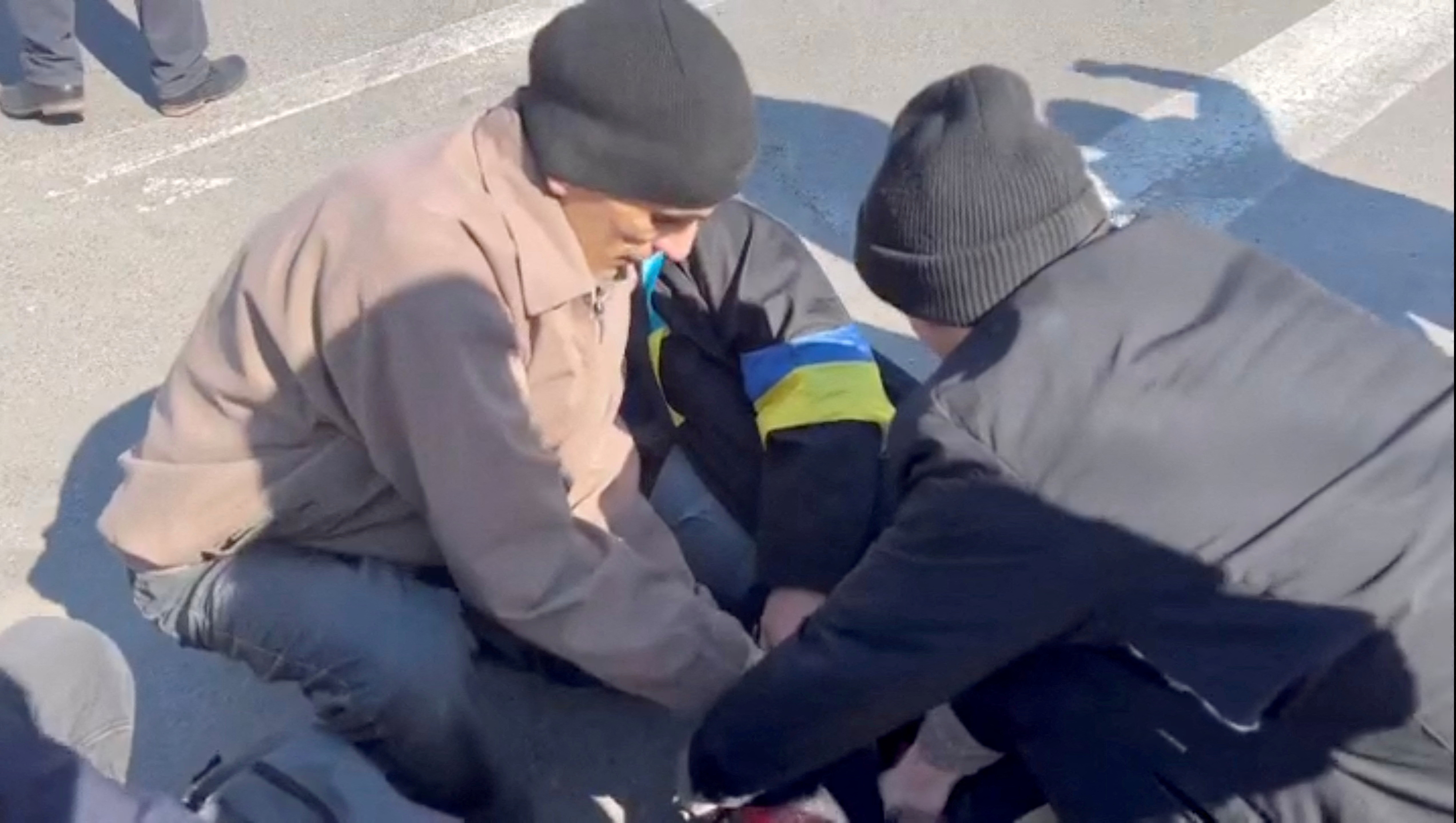 People help an injured demonstrator after Russian troops used stun grenades and gunfire to disperse a protest in Kherson